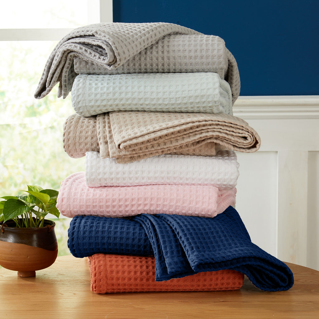 Brielle Collection Cotton Waffle Blanket by Market & Place featuring soft, breathable 100% cotton construction with a classic waffle weave texture. Available in multiple colors and shown folded, layered on beds, and in detailed fabric close-ups, highlighting its lightweight comfort and versatile year-round style.