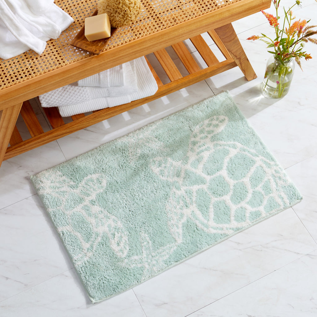Coastal-themed bath rug featuring sea turtle silhouettes in white on a soft seafoam green background. The plush, absorbent design brings a relaxing beach-inspired look while adding comfort and texture to bathroom décor.