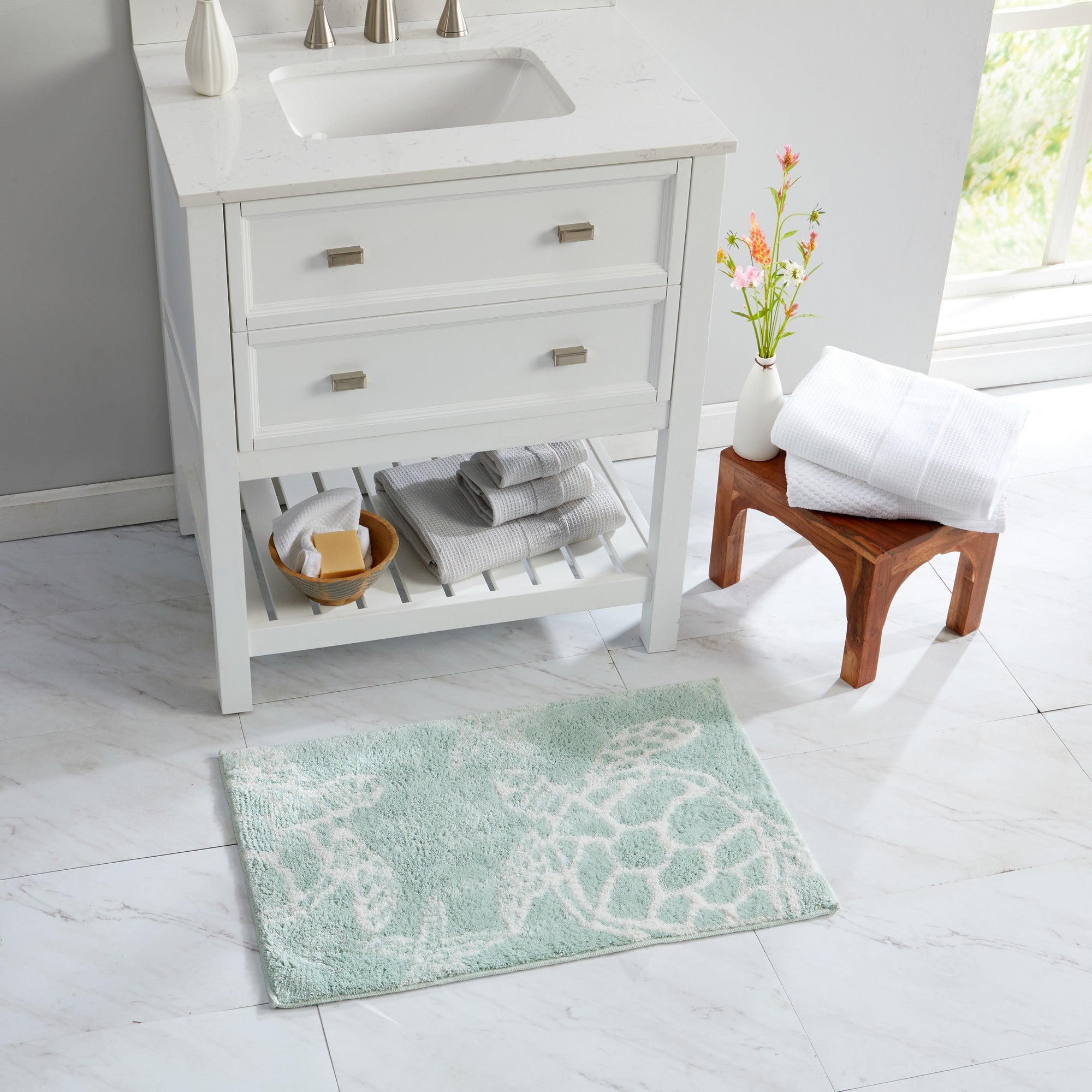 Coastal-themed bath rug featuring sea turtle silhouettes in white on a soft seafoam green background, styled in a bright bathroom setting. The plush, absorbent rug adds a relaxing beach-inspired touch while providing comfort and texture underfoot.
