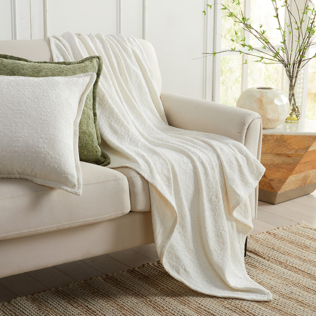 White Charlotte Collection Chenille Jacquard Throw Blanket draped over sofa with coordinating decorative pillows, soft textured chenille fabric for cozy farmhouse and modern home décor.