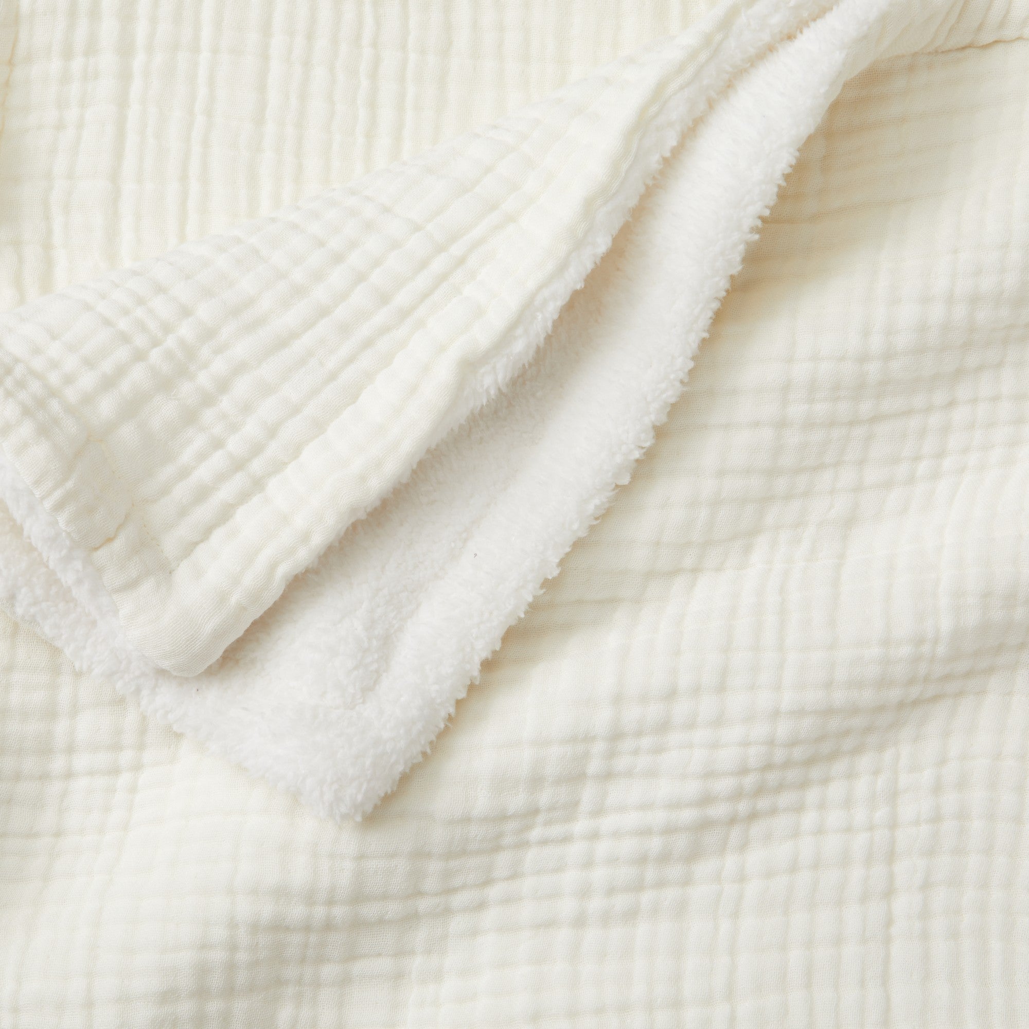 Close-up of the Off-White Maria Collection cotton muslin sherpa throw blanket, highlighting the textured cotton muslin face and ultra-soft sherpa backing.