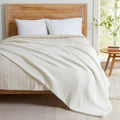 Off-White Maria Collection cotton muslin blanket draped across a bed, featuring a soft textured muslin weave and lightweight design that adds cozy comfort and effortless style to any bedroom.