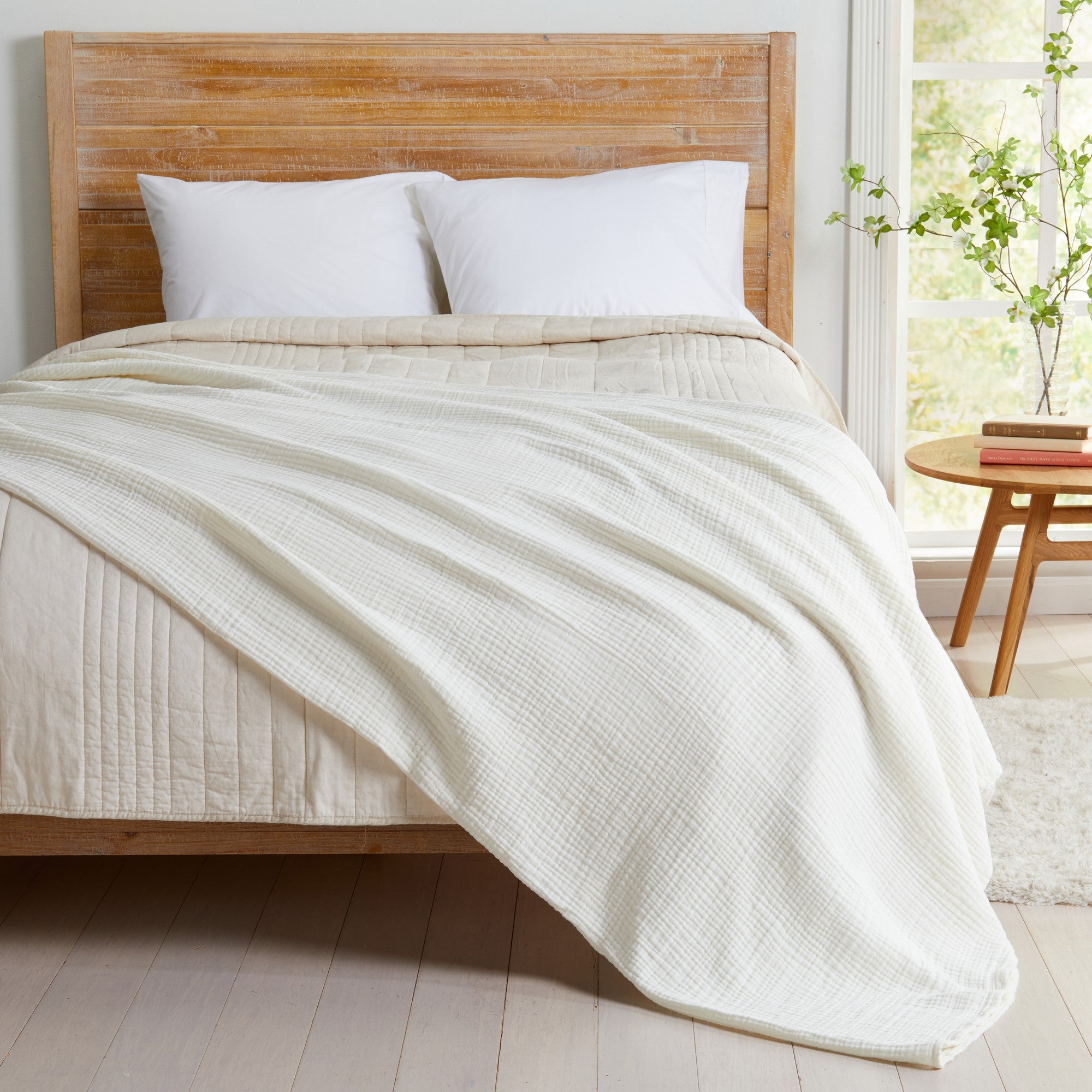 Off-White Maria Collection cotton muslin blanket draped across a bed, featuring a soft gauze texture, breathable multi-layer construction, and elegant neutral color. The lightweight blanket creates a cozy, relaxed look while adding comfort and timeless style to the bedroom.