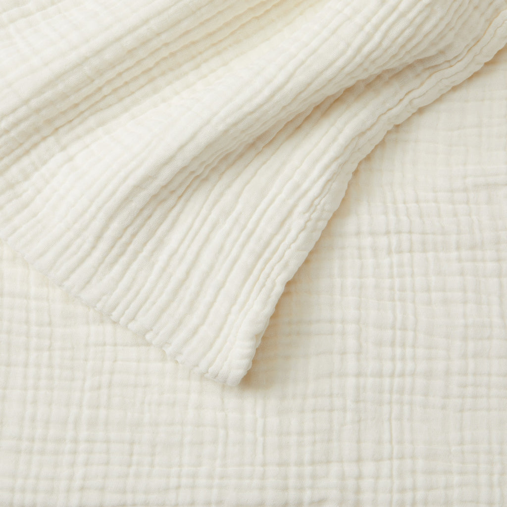 Close-up detail of the Off-White Maria Collection cotton muslin blanket showcasing its soft gauze texture, layered construction, and breathable fabric. The image highlights the blanket’s relaxed woven appearance and cozy, lightweight feel.