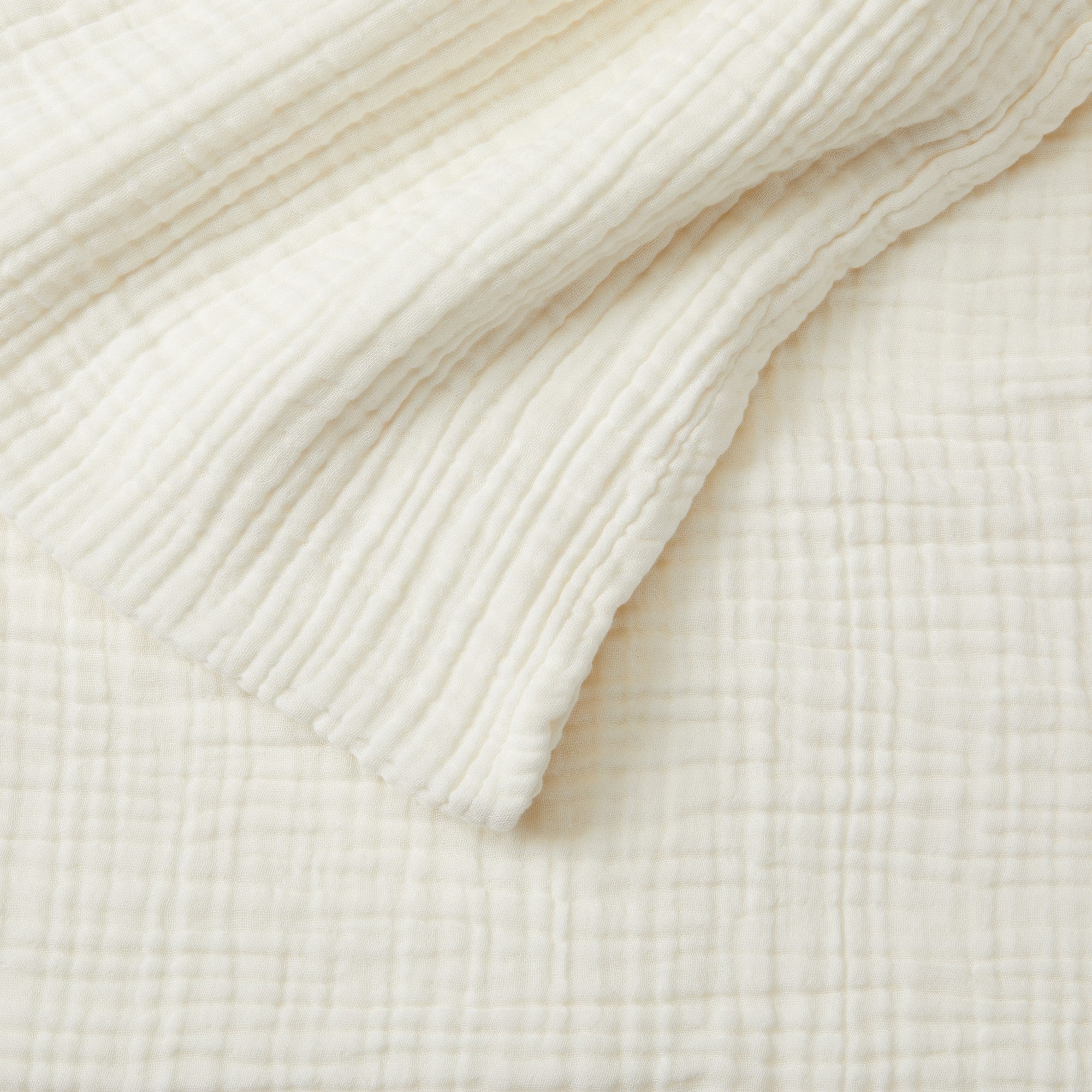 Close-up detail of the Off-White Maria Collection cotton muslin blanket showcasing its soft gauze texture, layered construction, and breathable fabric. The image highlights the blanket’s relaxed woven appearance and cozy, lightweight feel.