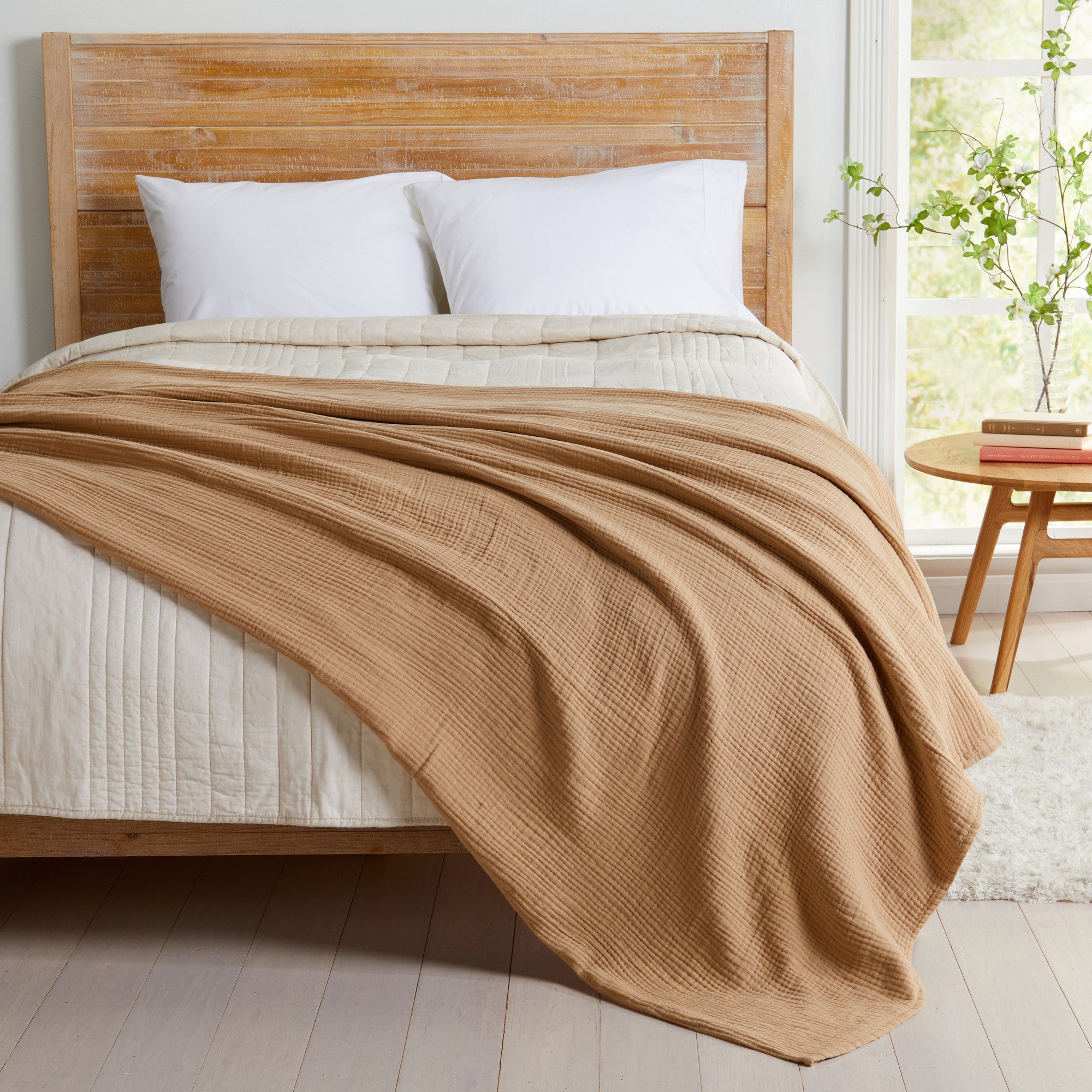 Beige Maria Collection cotton muslin blanket draped across a bed, showcasing a soft textured weave and lightweight breathable design. The warm neutral beige color adds a cozy, natural touch to the bedroom while providing year-round comfort and casual elegance.