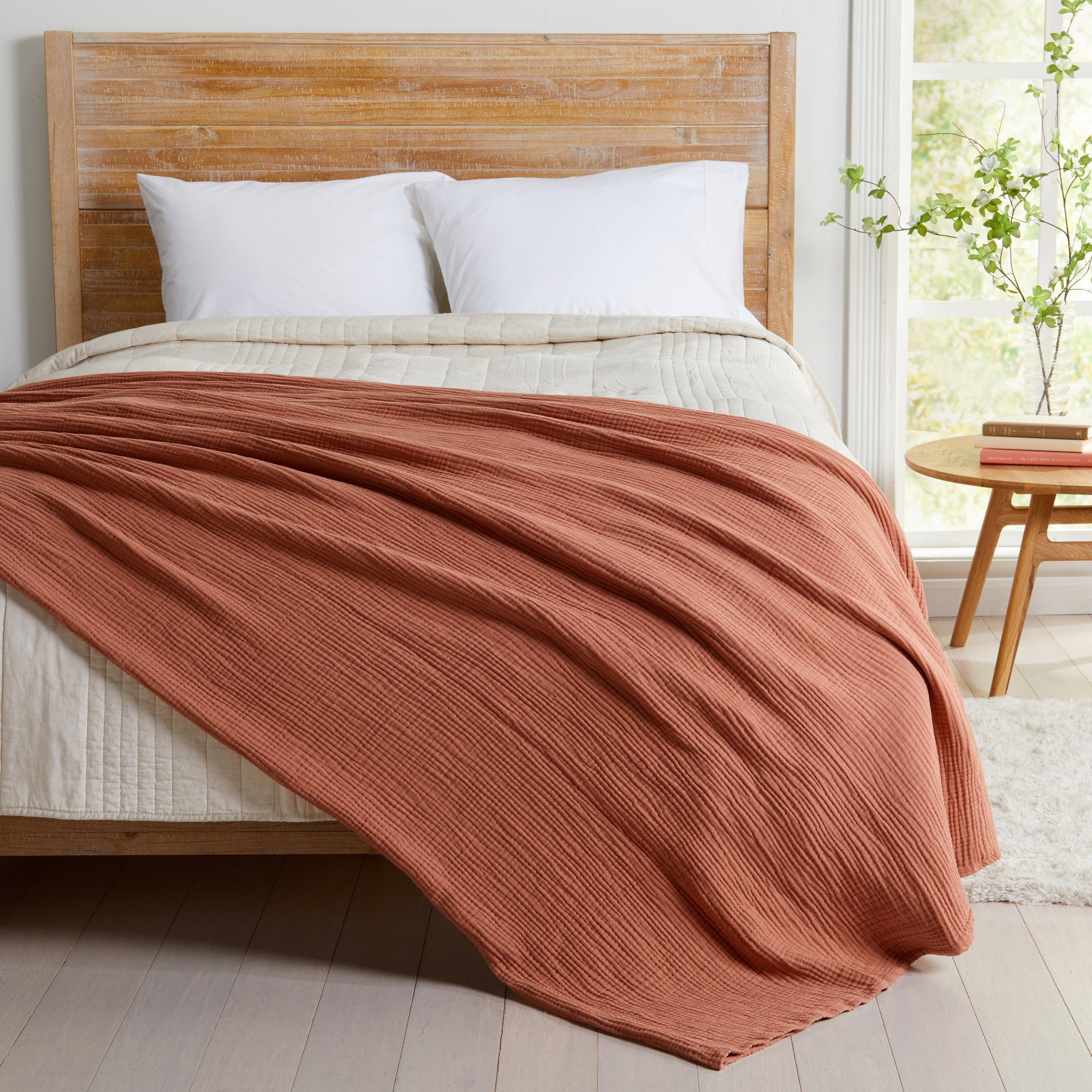 Rust Maria Collection cotton muslin blanket draped across a bed, featuring a soft textured weave and lightweight breathable fabric. The rich rust color adds warmth and character to the bedroom while offering cozy comfort and a relaxed, modern aesthetic for year-round use.