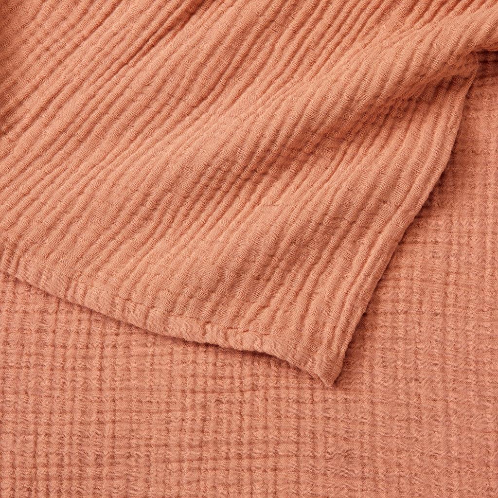 Close-up detail of the Rust Maria Collection cotton muslin blanket showcasing its soft gauze texture, breathable multi-layer weave, and warm earthy color. The image highlights the blanket’s lightweight construction, natural crinkled finish, and cozy casual style.