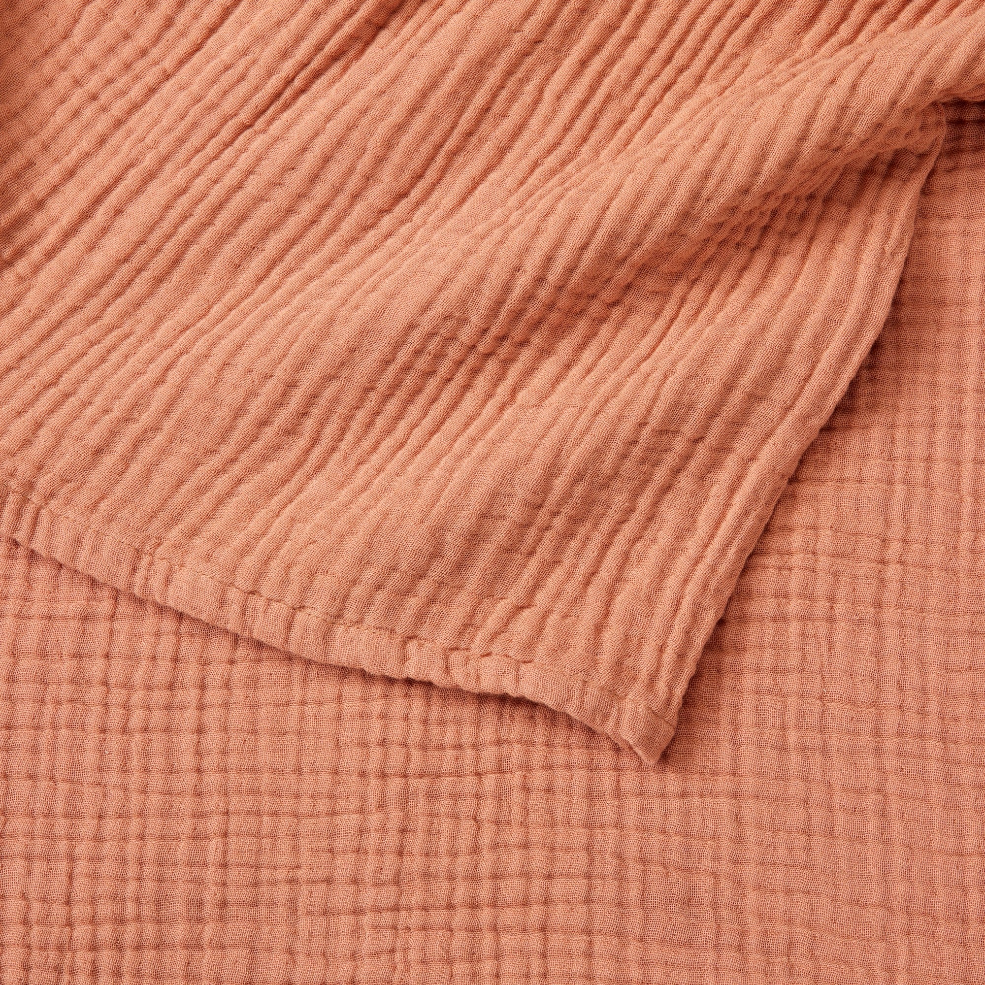 Close-up detail of the Rust Maria Collection cotton muslin blanket showcasing its soft gauze texture, breathable multi-layer weave, and warm earthy color. The image highlights the blanket’s lightweight construction, natural crinkled finish, and cozy casual style.