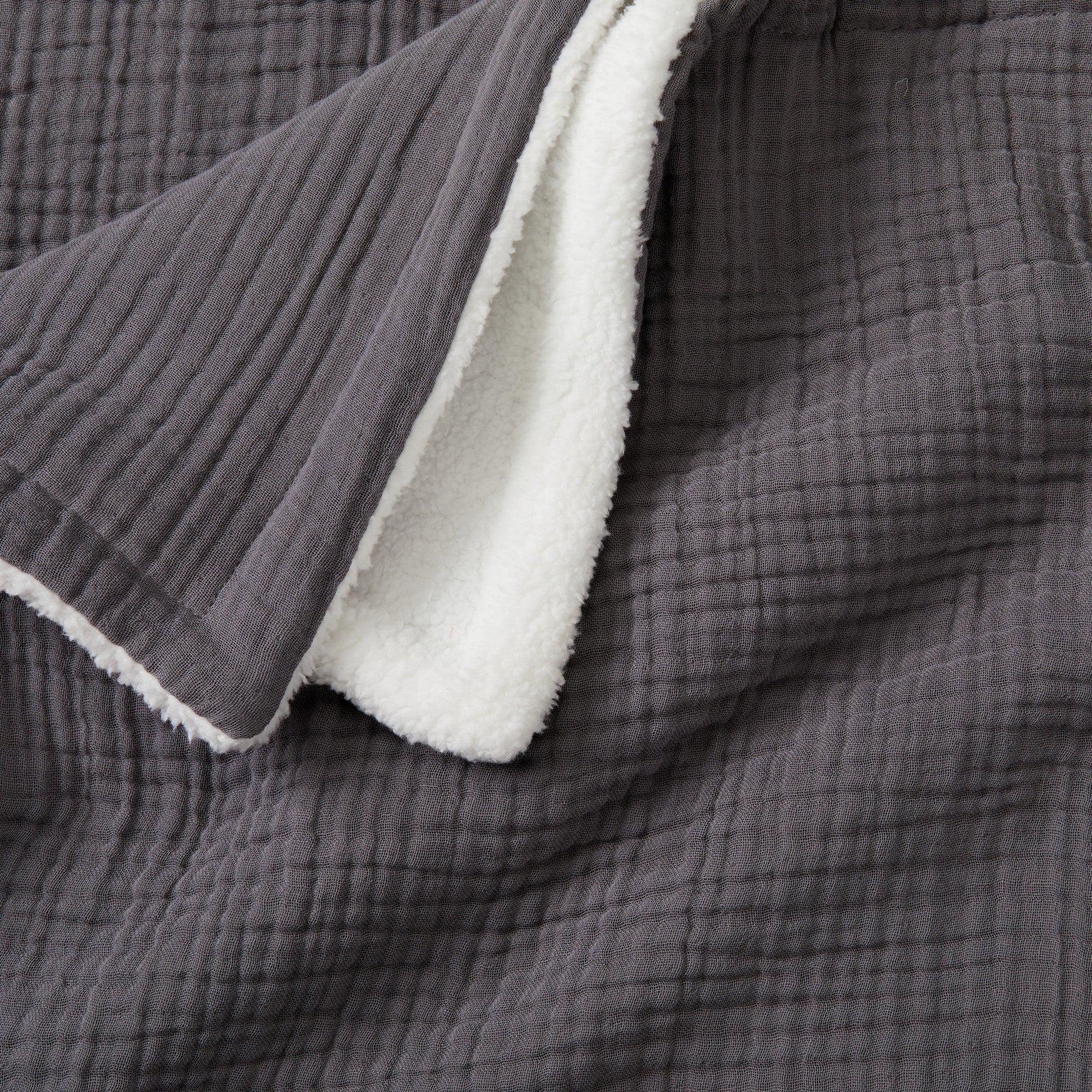 Close-up of the Charcoal Maria Collection cotton muslin sherpa throw blanket, featuring a textured cotton muslin surface with a plush sherpa reverse for exceptional softness and warmth.