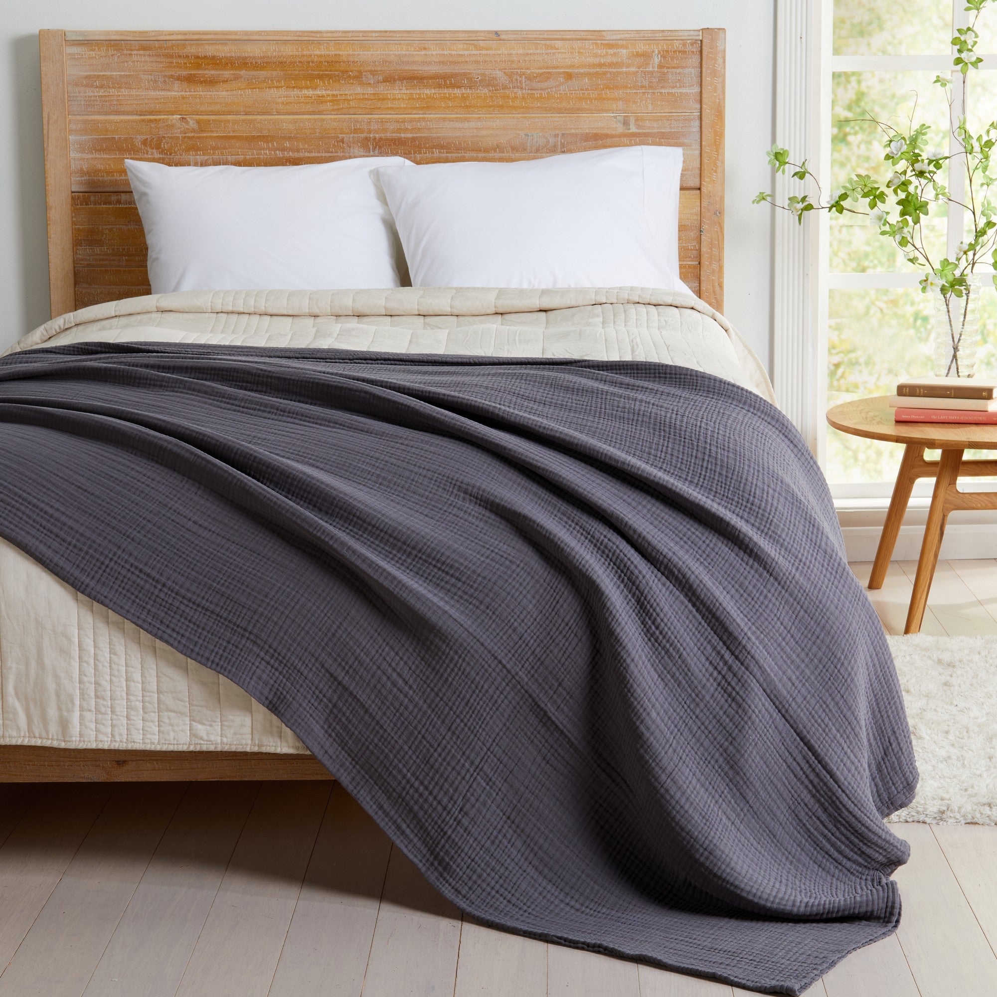 Charcoal Maria Collection cotton muslin blanket draped across a bed, featuring a soft textured muslin weave and lightweight construction that delivers cozy comfort and modern style for any bedroom décor.
