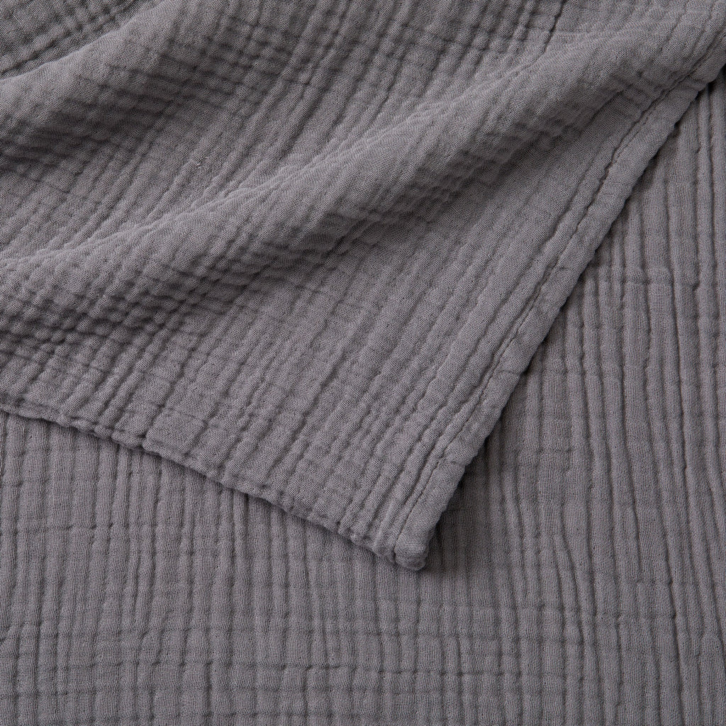 Close-up detail of the Charcoal Maria Collection cotton muslin blanket showcasing its soft gauze texture, breathable multi-layer weave, and rich charcoal gray color. The image highlights the blanket’s lightweight construction, natural crinkled finish, and relaxed contemporary style.