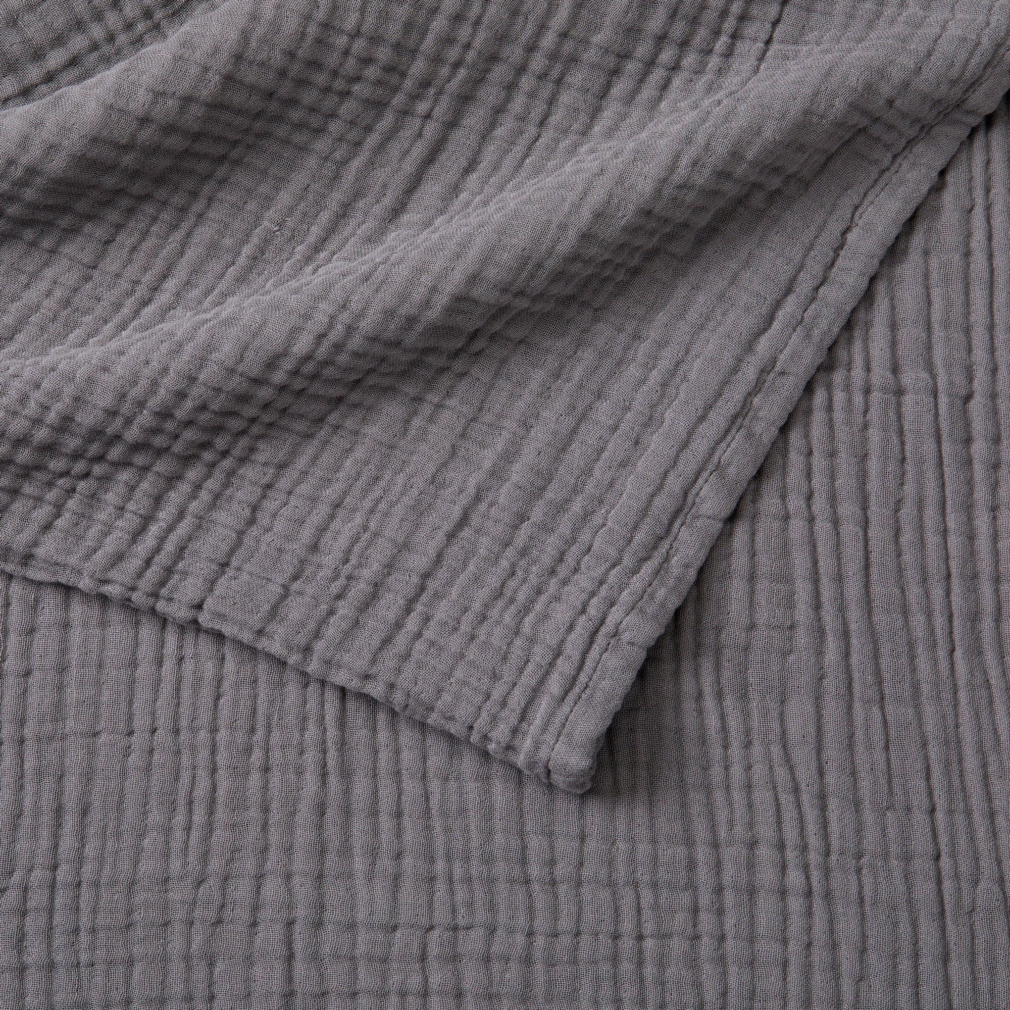Close-up detail of the Charcoal Maria Collection cotton muslin blanket showcasing its soft gauze texture, breathable multi-layer weave, and rich charcoal gray color. The image highlights the blanket’s lightweight construction, natural crinkled finish, and relaxed contemporary style.
