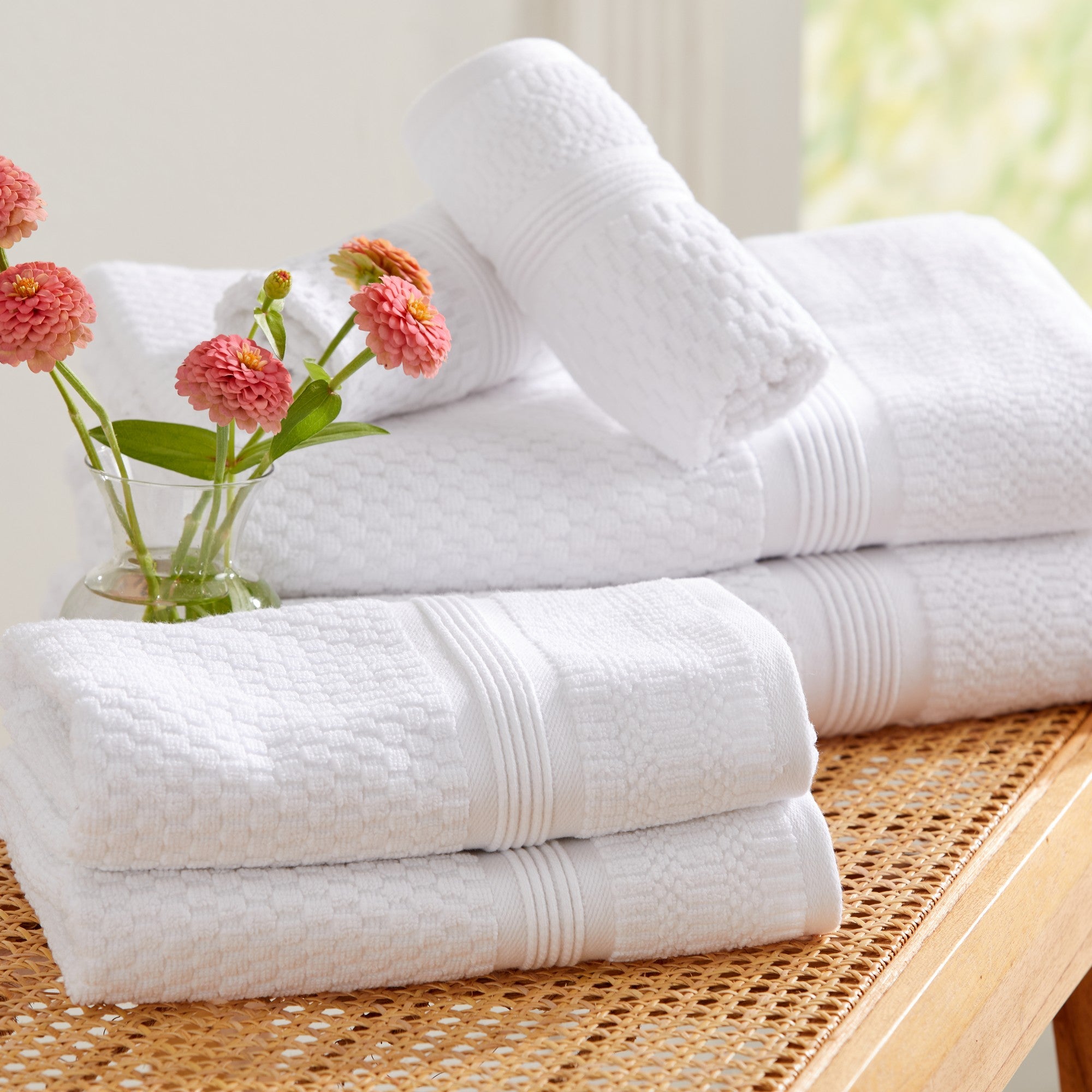 White waffle weave cotton bath towel set stacked on wooden bench
