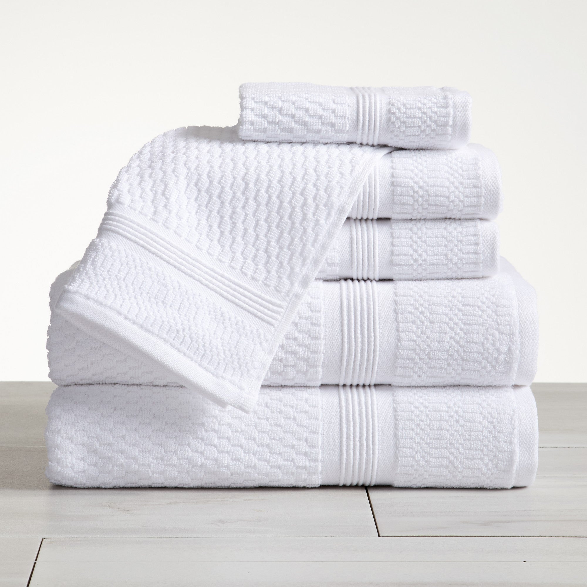 White waffle weave cotton bath towel set stacked on white surface