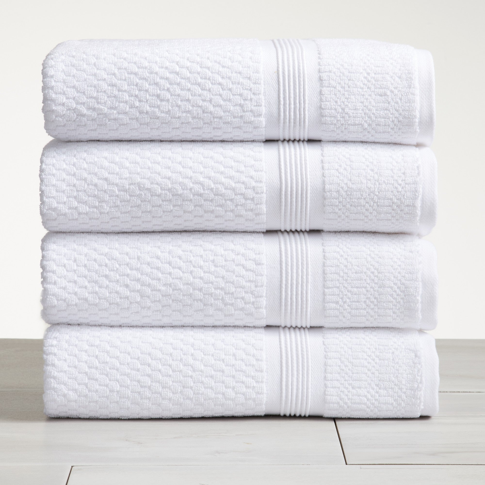 White waffle weave cotton bath towels stacked on white surface