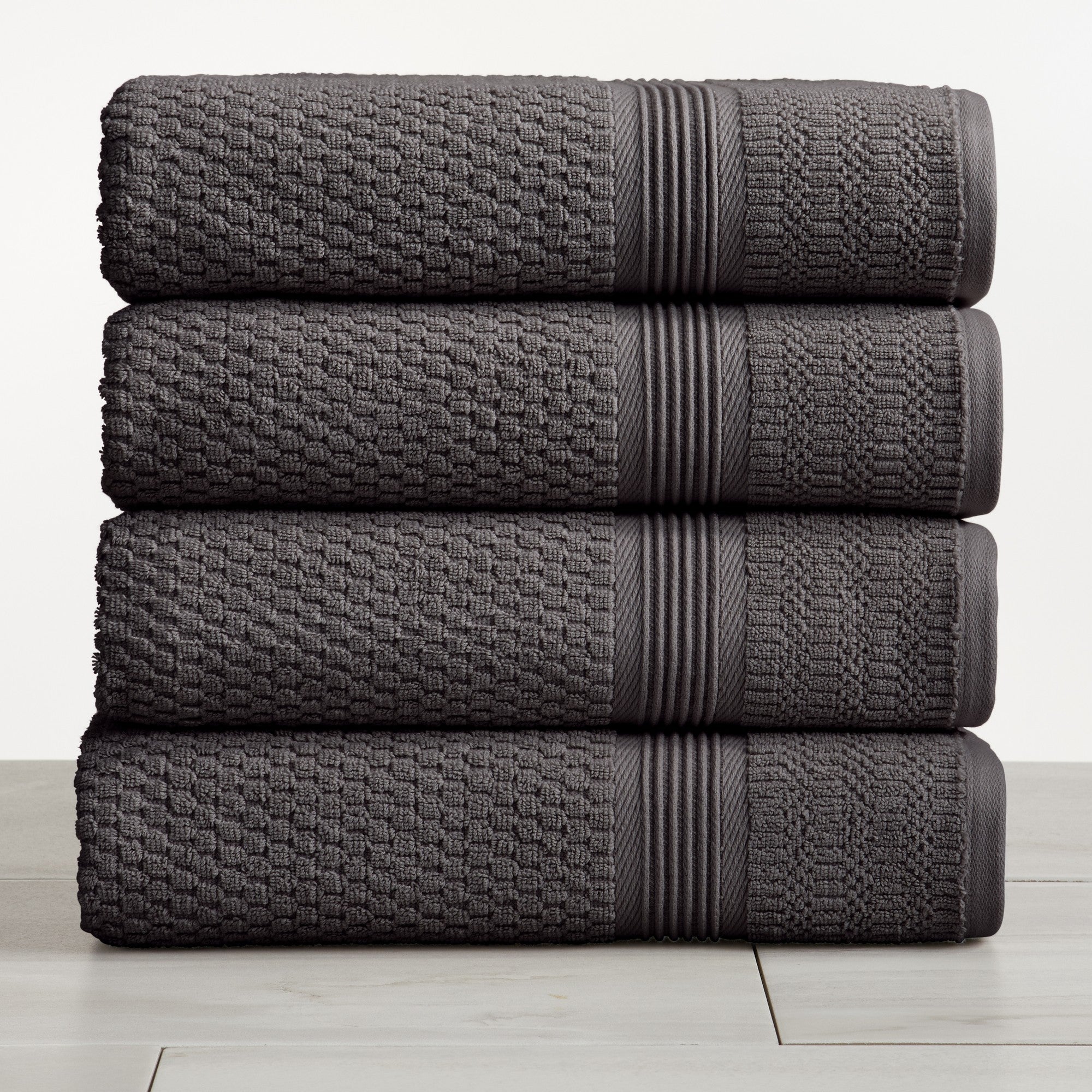 Charcoal waffle weave cotton bath towels stacked on white surface