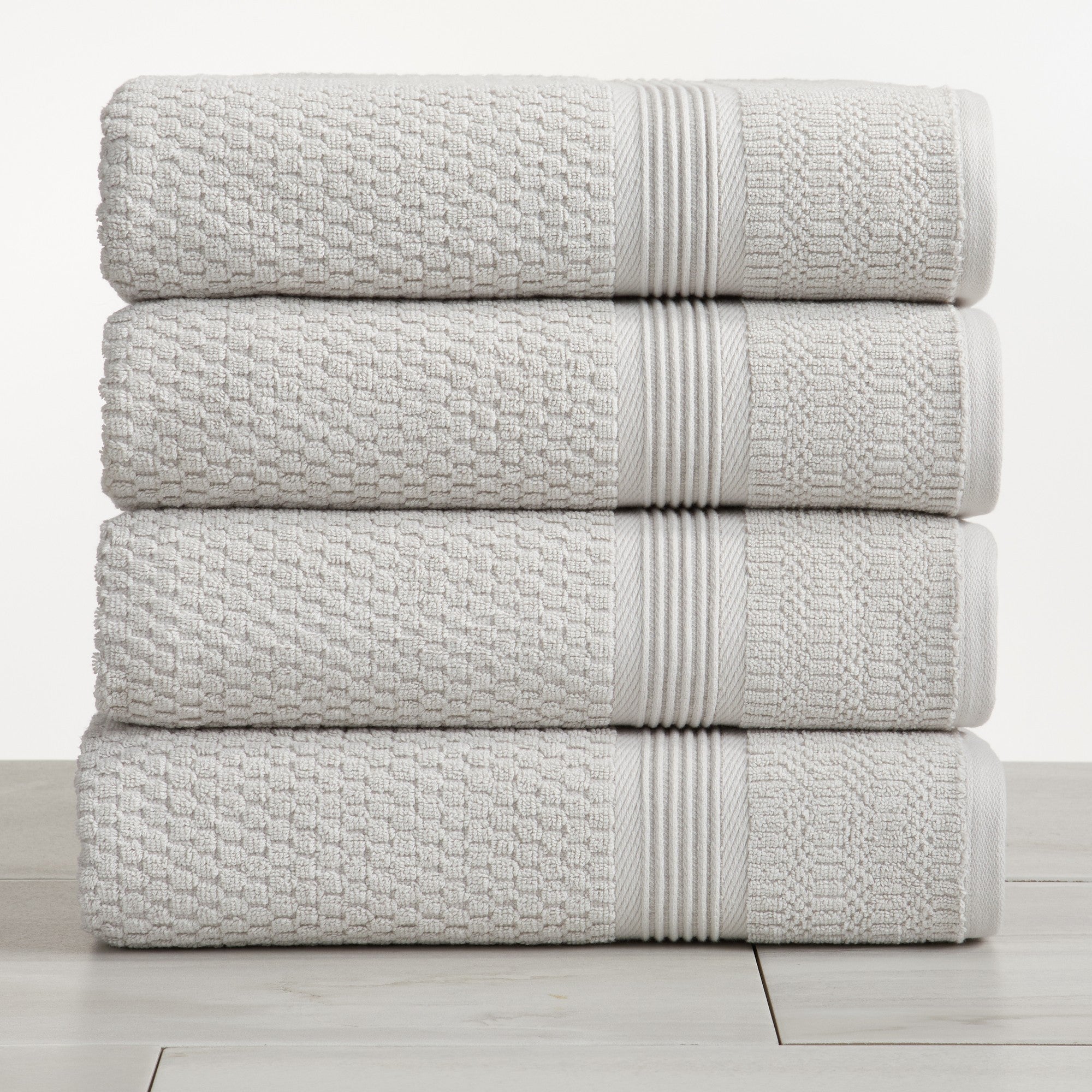 Ivory waffle weave cotton bath towels stacked on white surface