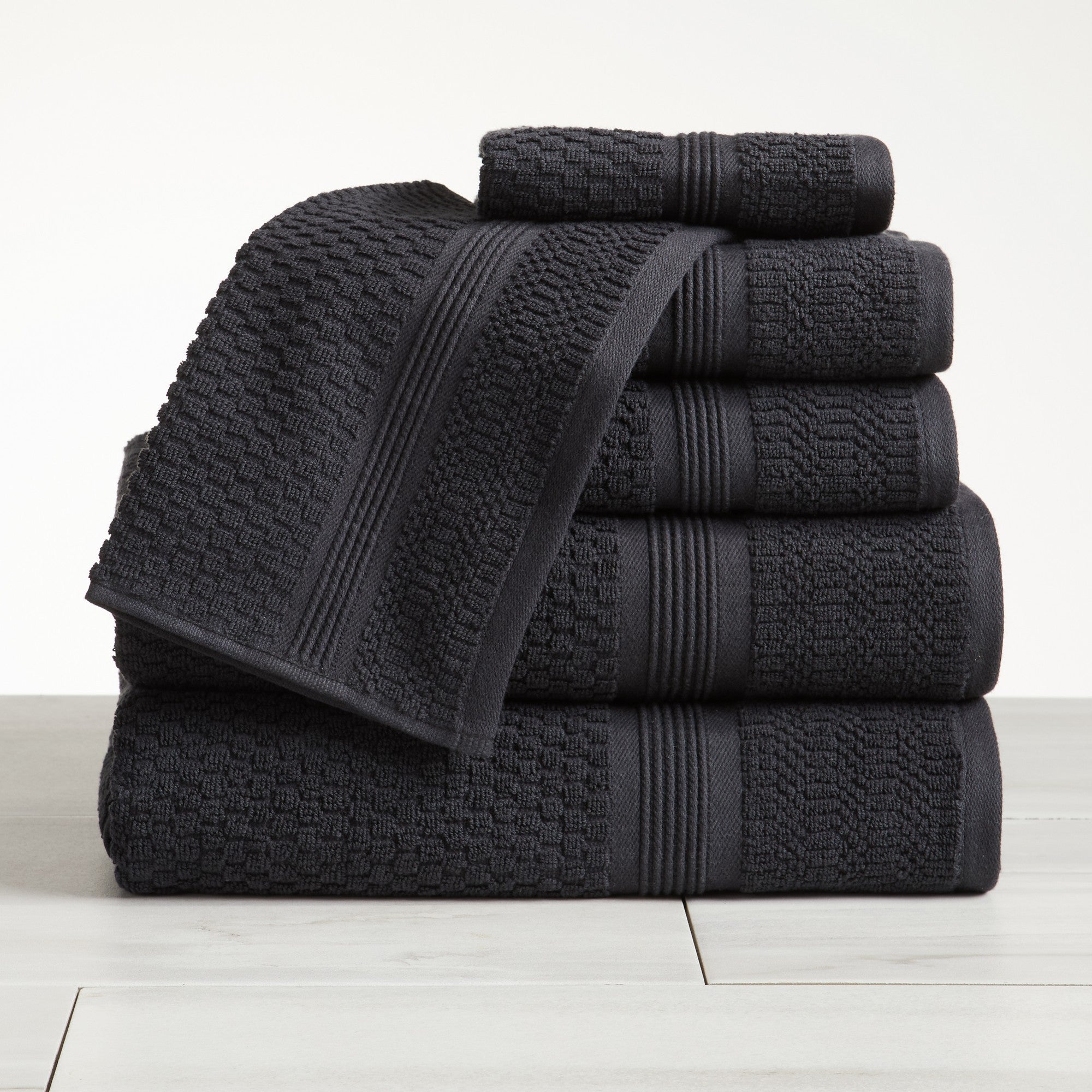 Charcoal waffle weave cotton bath towel set stacked on white surface