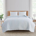 Avery Collection reversible striped quilt set in blue and white displayed on a bed with matching pillow shams