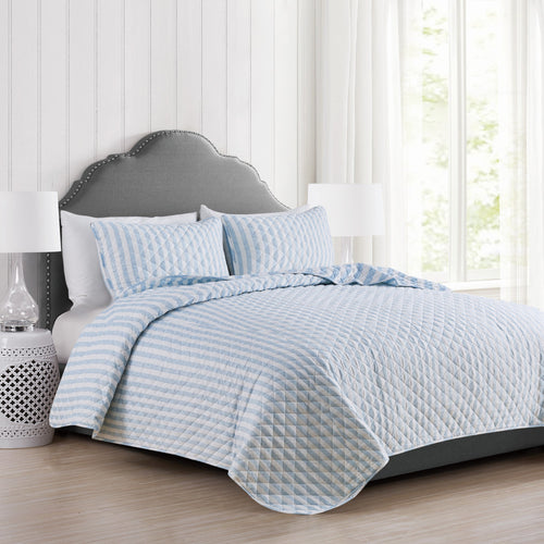 Avery Collection reversible blue and white striped quilt set displayed on a bed with matching pillow shams