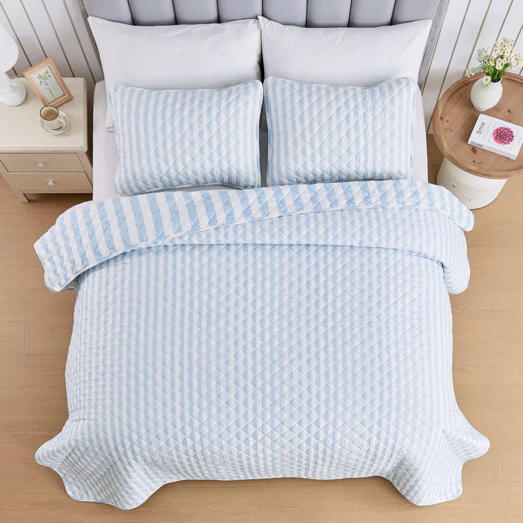 Overhead view of Avery Collection reversible blue and white striped quilt set with matching pillow shams