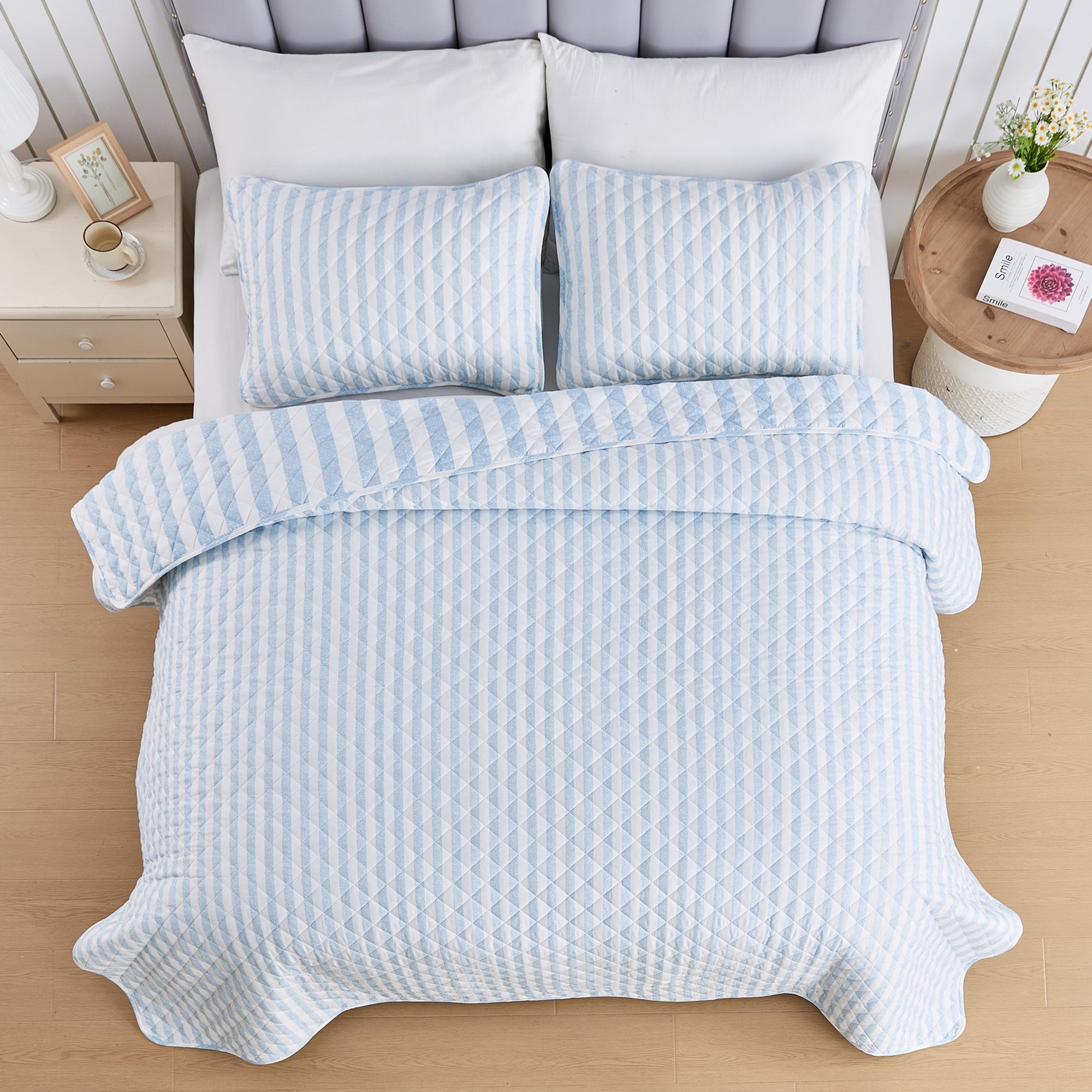 Overhead view of Avery Collection reversible blue and white striped quilt set with matching pillow shams