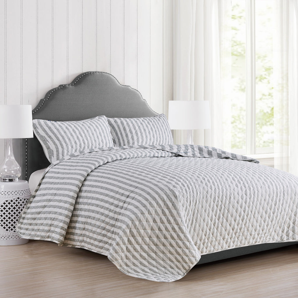Avery Collection reversible gray and white striped quilt set styled on a bed with matching pillow shams