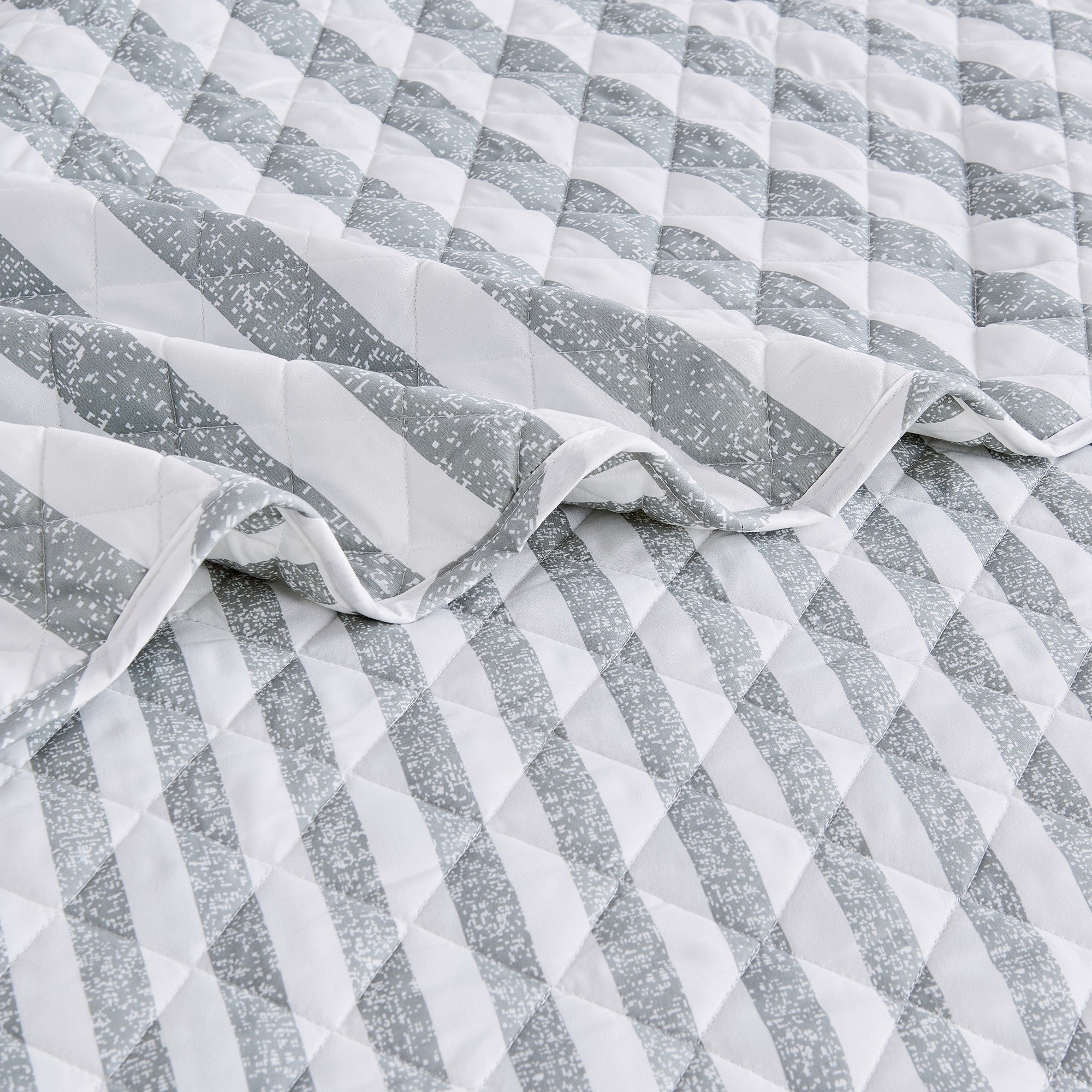 Close-up of Avery Collection gray and white striped quilt showcasing diamond quilting and soft microfiber fabric
