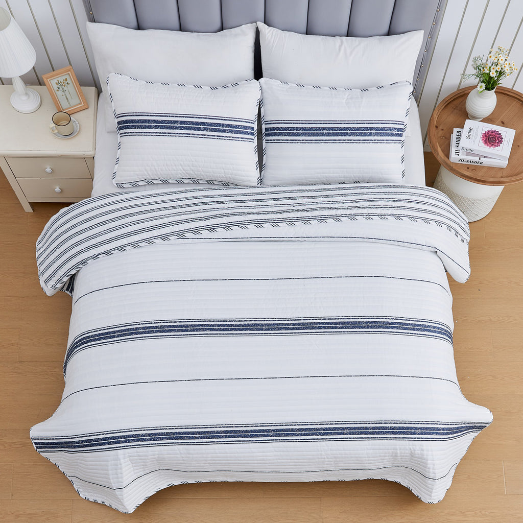 Harper Collection striped quilt set displayed from above, featuring white fabric with navy blue horizontal stripe accents and matching pillow shams.