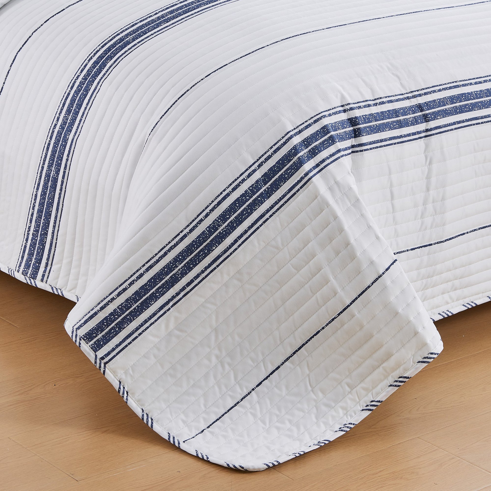 Close-up of the Harper Collection quilt featuring navy blue stripe accents, channel quilting, and soft microfiber fabric.