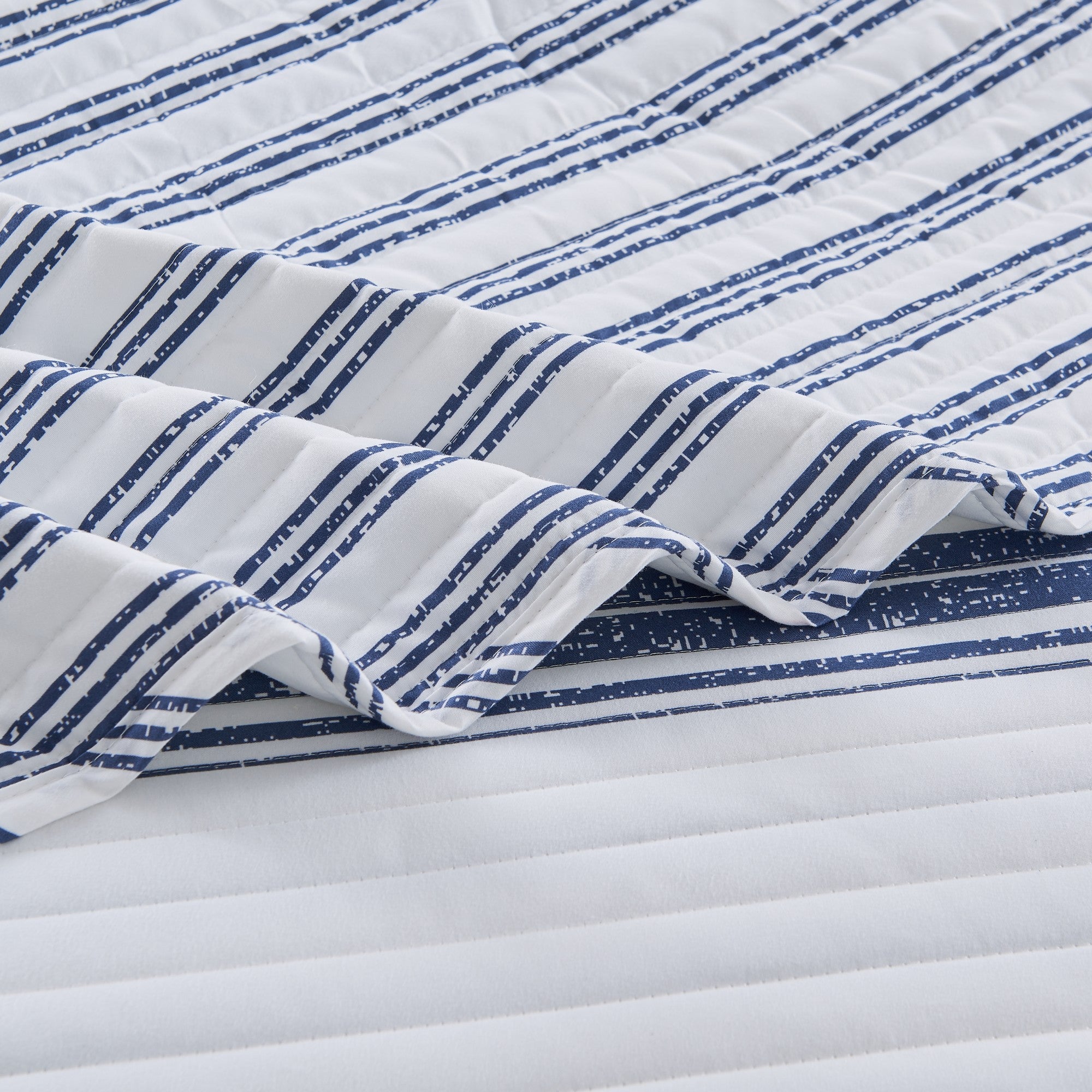 Close-up detail of the Harper Collection quilt showcasing navy blue striped fabric, quilted stitching, and soft microfiber construction.
