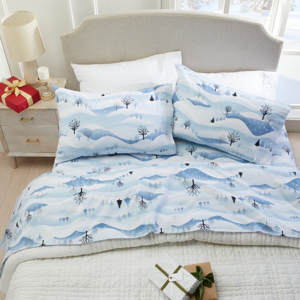 Printed 100% Turkish cotton flannel sheet set featuring assorted winter-inspired patterns, including woodland animals, snowflakes, trees, plaids, and seasonal motifs. Soft, cozy bedding shown in styled bedroom settings with close-up fabric details and folded sheet stacks in multiple designs.