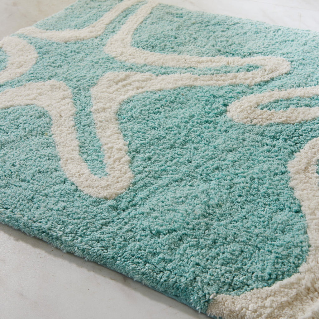 Teal rug with white geometric pattern on a light background