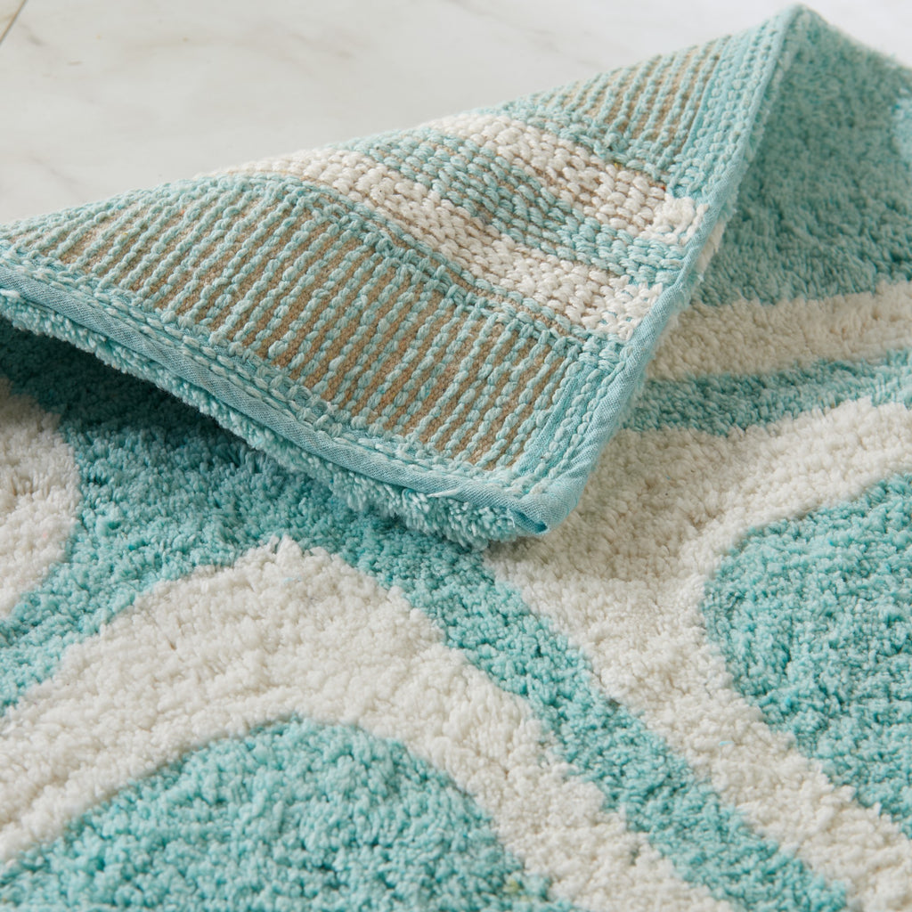 Close-up of a textured teal and beige rug with geometric pattern