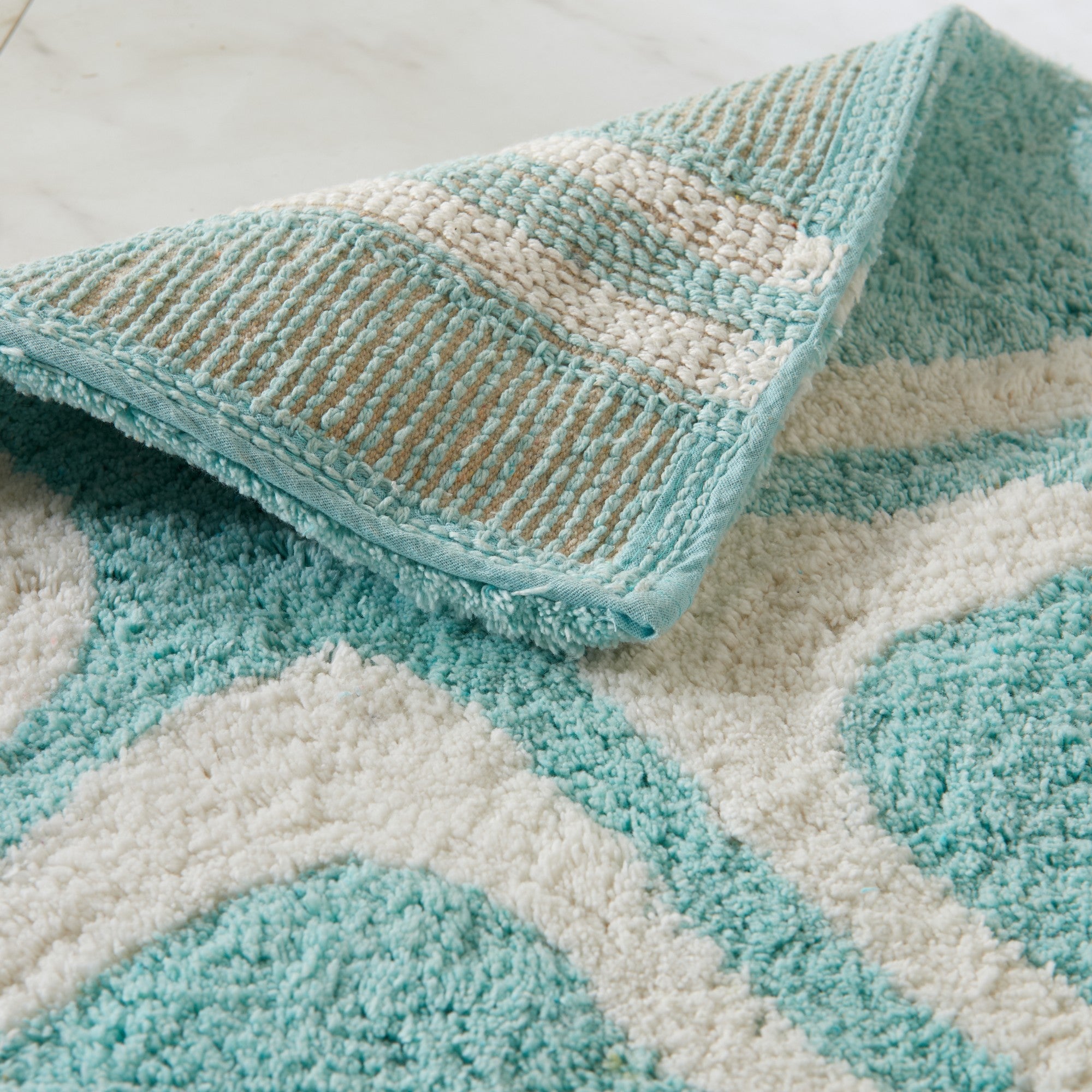 Close-up of a textured teal and beige rug with geometric pattern