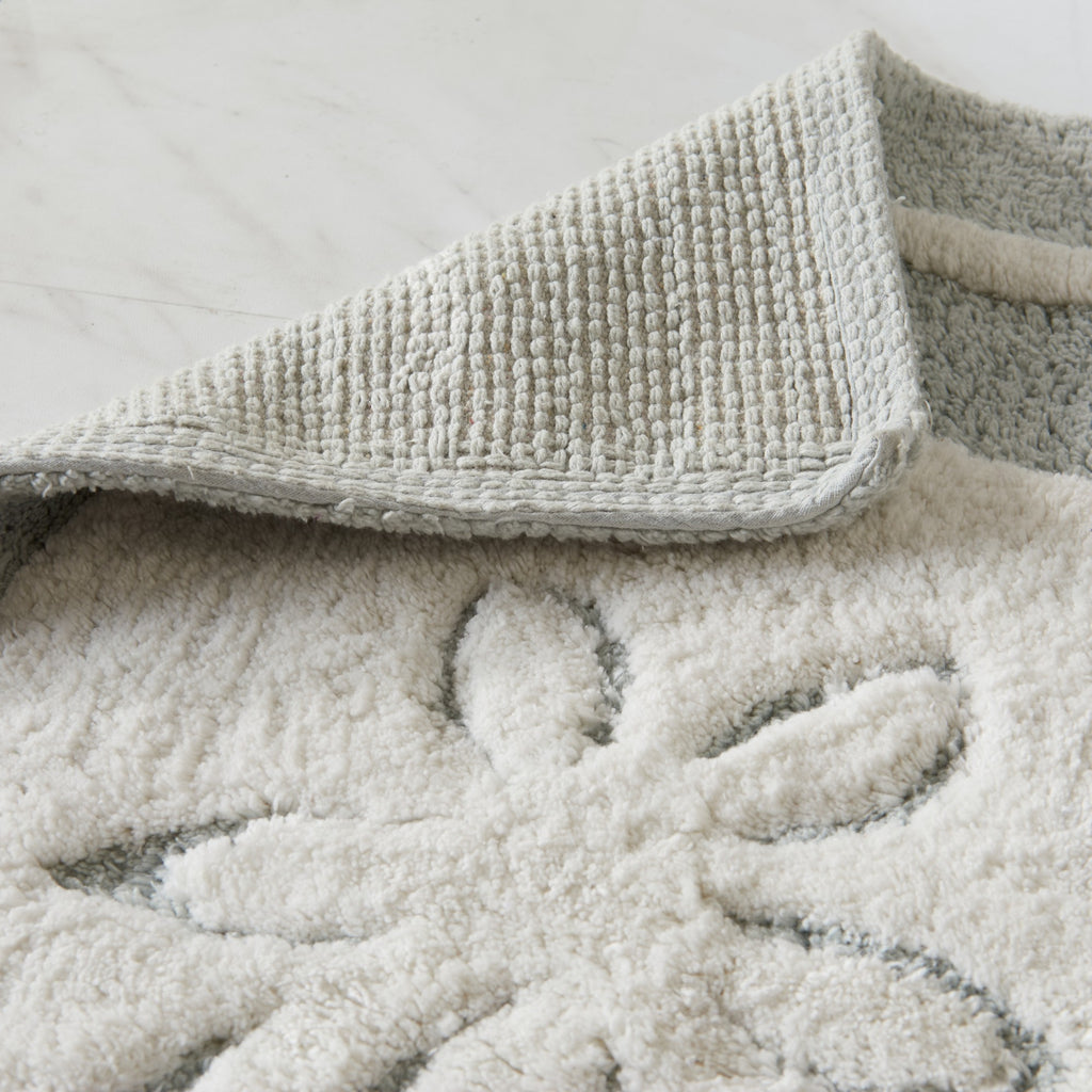 Close-up of textured bath mat with floral pattern on a light background