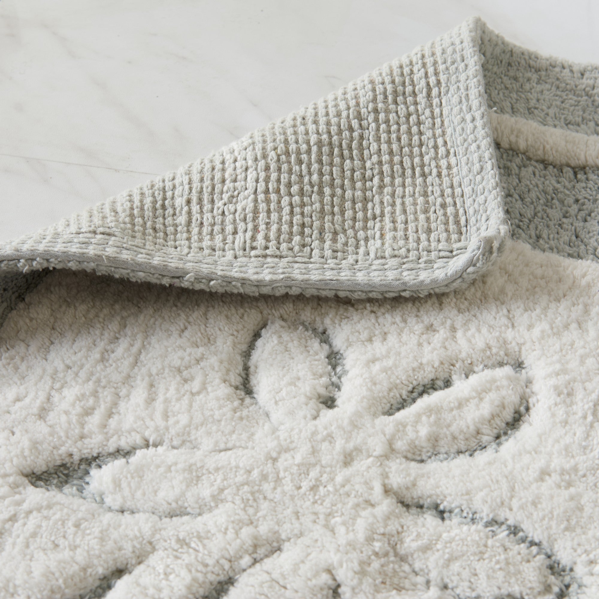 Close-up of textured bath mat with floral pattern on a light background