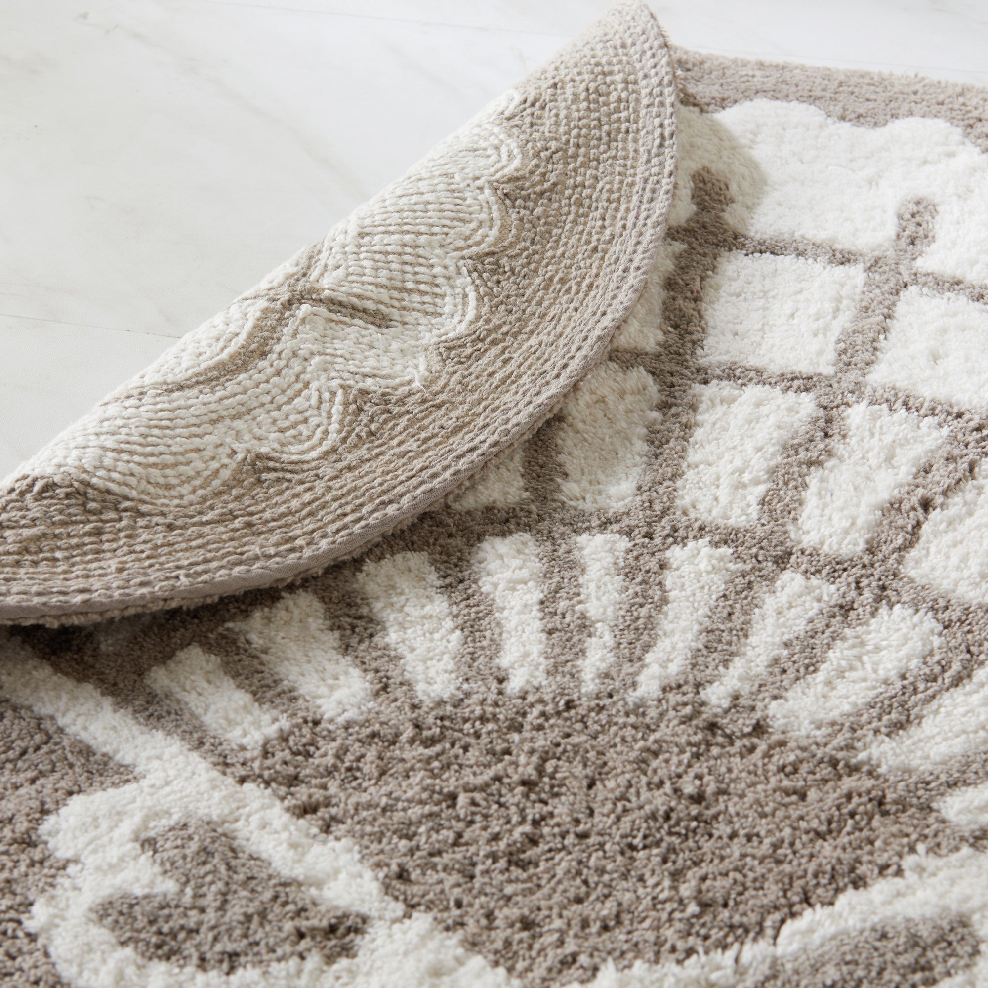 Close-up of a textured beige rug with geometric pattern on a light background