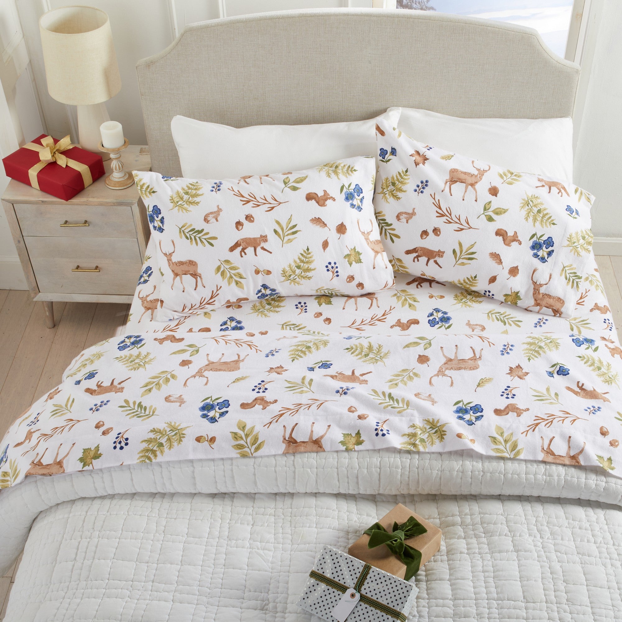 Floral and animal patterned bedding set on a bed with decorative items.