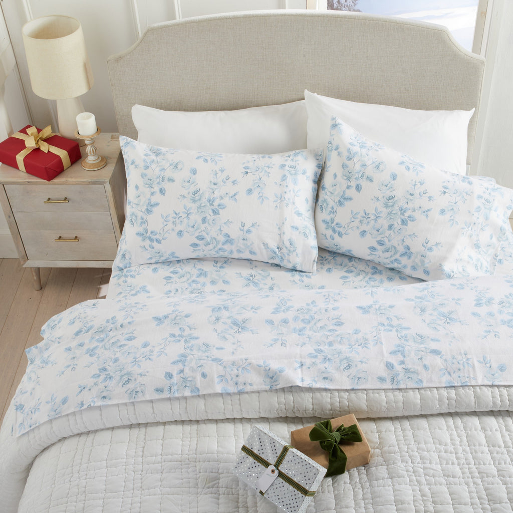 Floral patterned bedding set on a bed with a nightstand and decorative items.