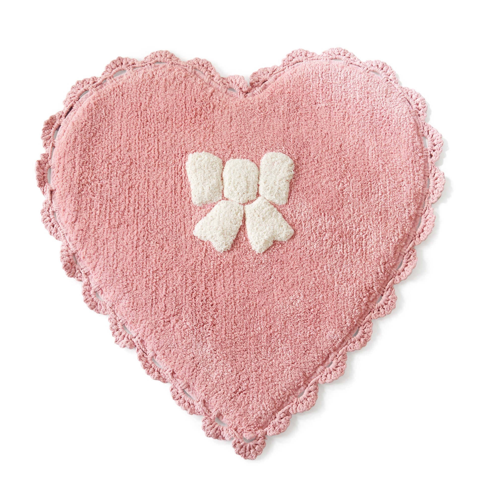 Heart-shaped pink pillow with a white bow on a white background