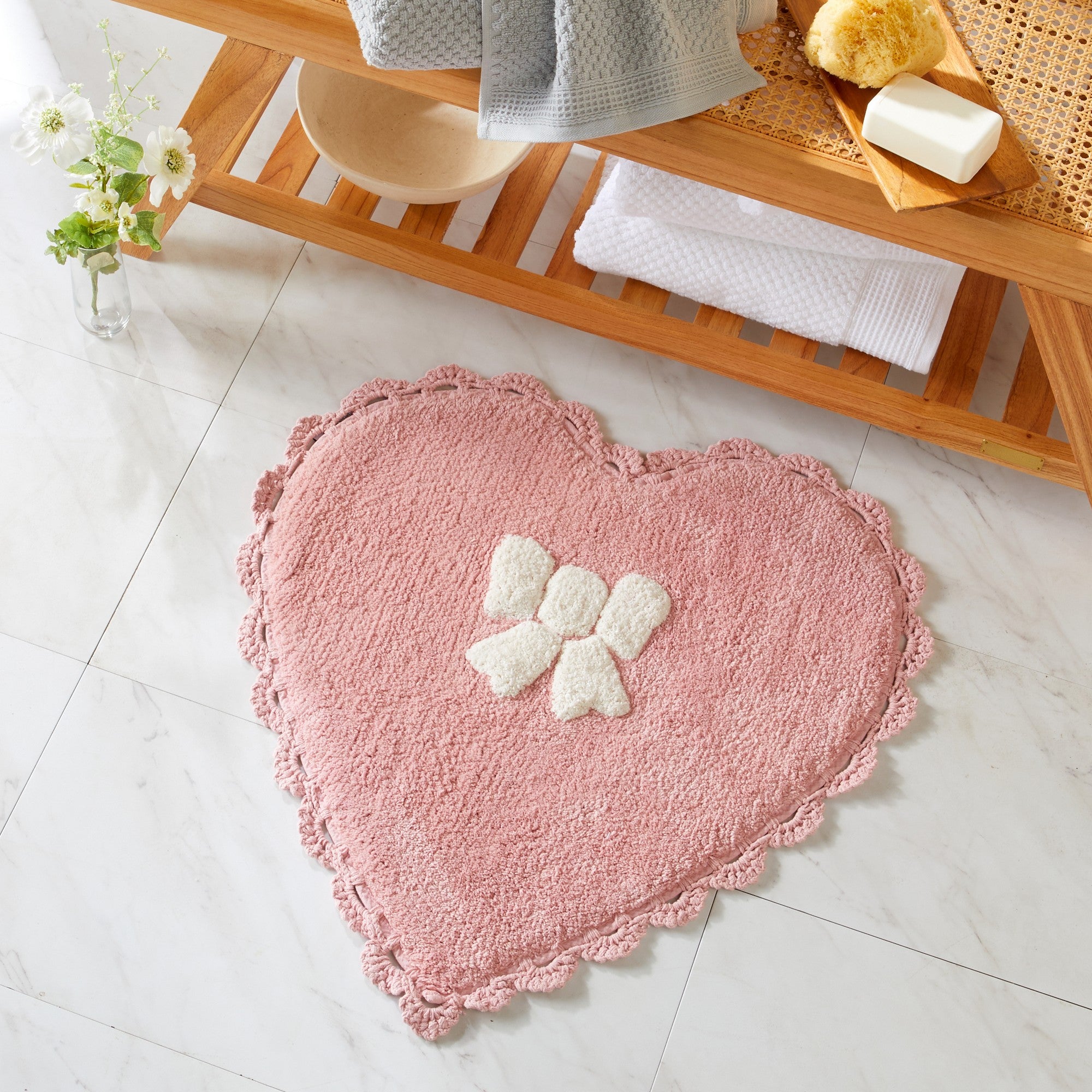 Heart-shaped pink rug with a white paw print design on a bathroom floor.