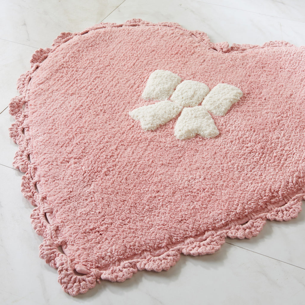 Pink heart-shaped rug with white butterfly design on a light gray floor.
