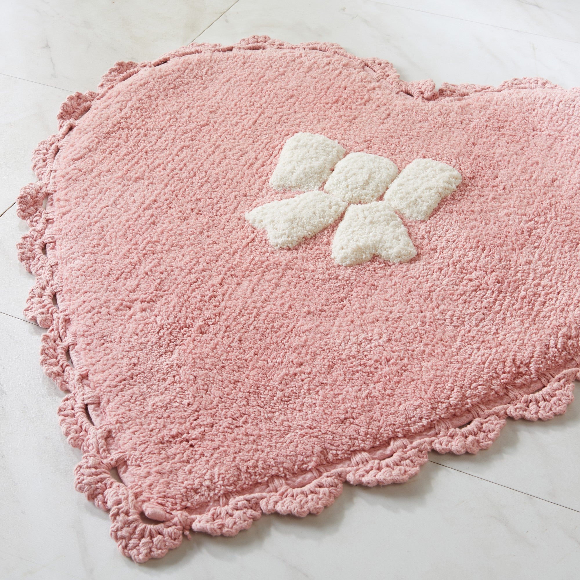Pink heart-shaped rug with white butterfly design on a light gray floor.