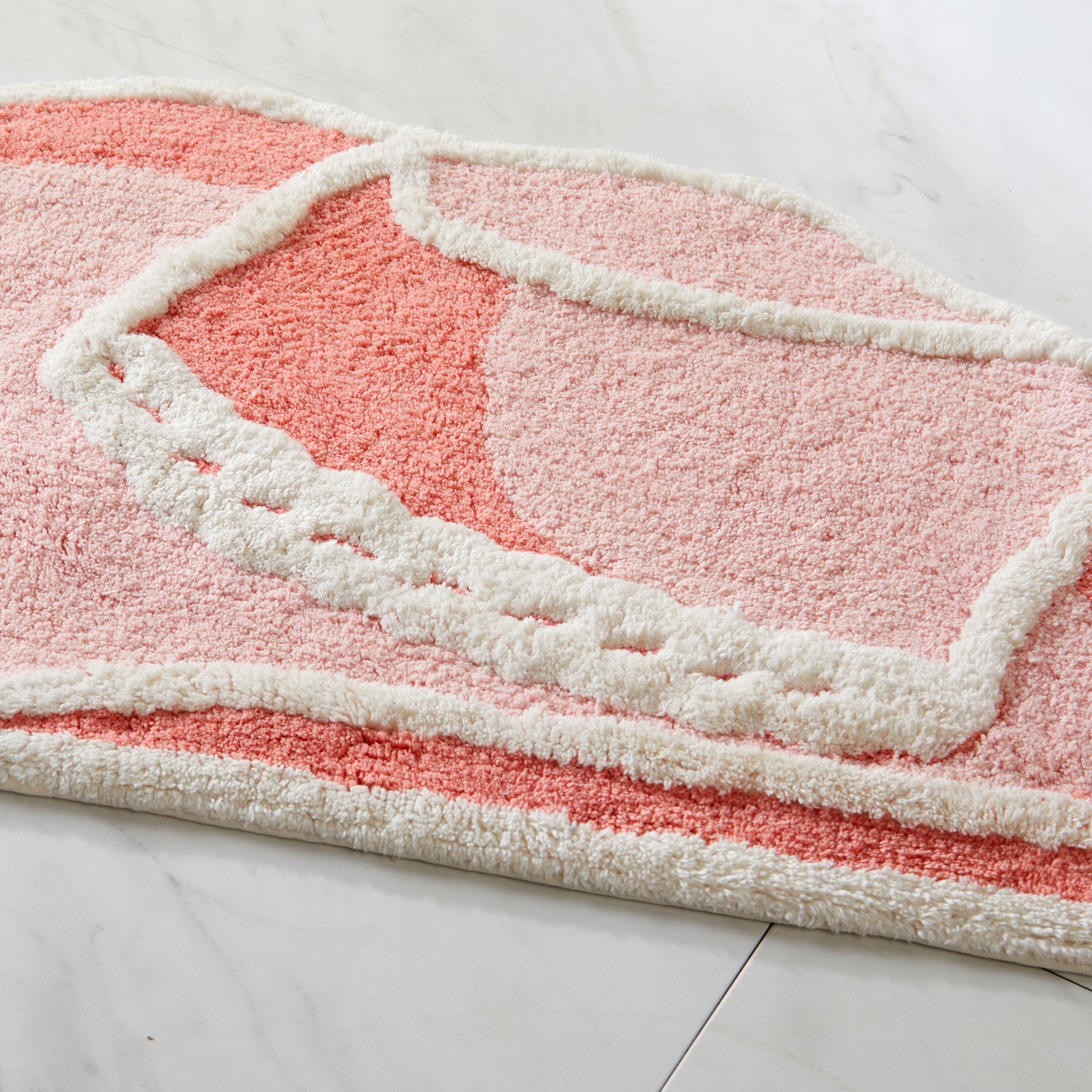 Pink and white textured rug on a light gray floor