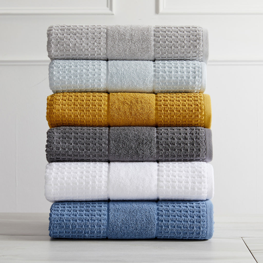 Harper Collection Waffle Textured Bath Towels by Market & Place featuring premium 100% cotton construction with a stylish waffle weave texture. Available in multiple colors and set configurations, including bath towels, hand towels, and washcloths, shown folded, stacked, and styled to highlight their soft, plush, and highly absorbent design.