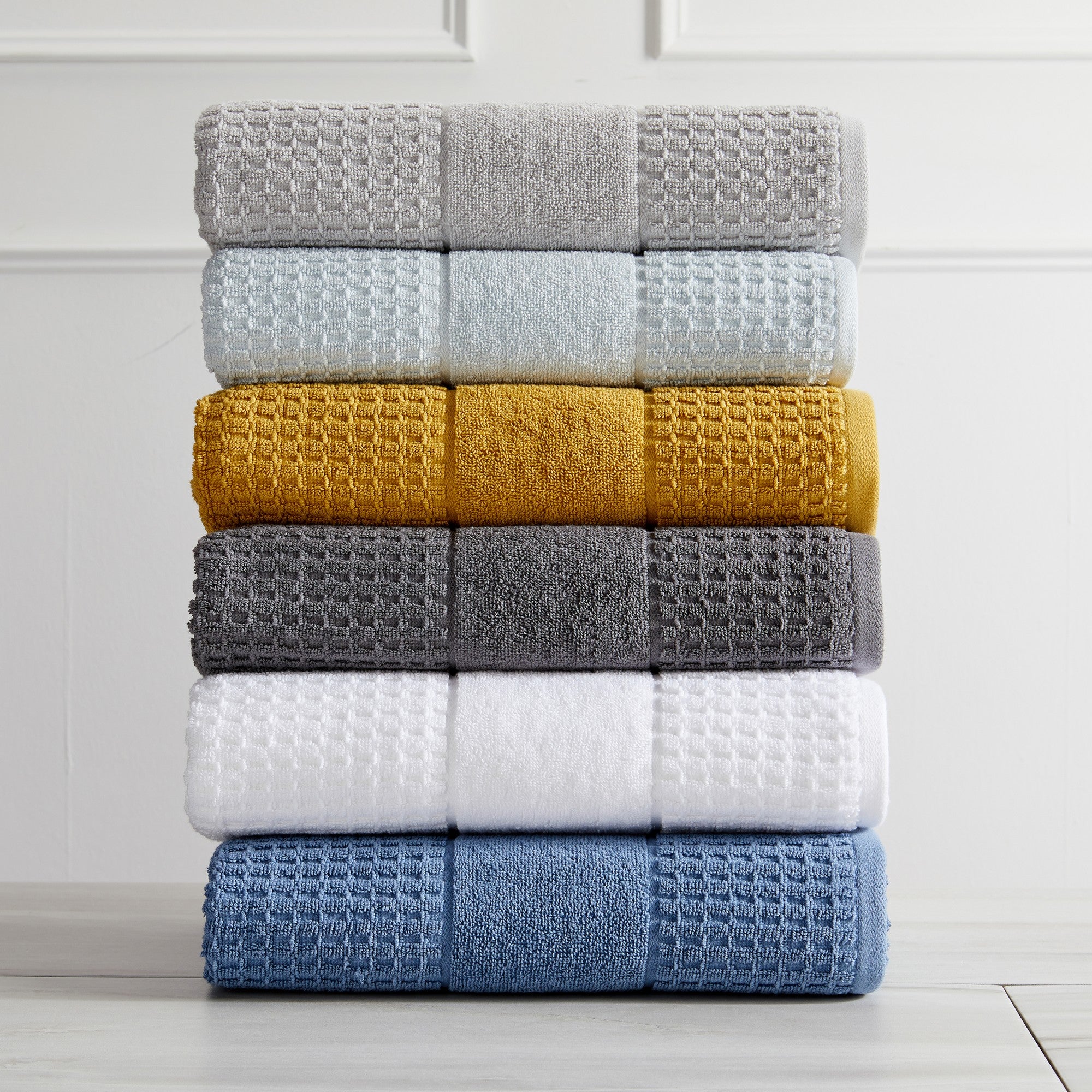 Harper Collection Waffle Textured Bath Towels by Market & Place featuring premium 100% cotton construction with a stylish waffle weave texture. Available in multiple colors and set configurations, including bath towels, hand towels, and washcloths, shown folded, stacked, and styled to highlight their soft, plush, and highly absorbent design.