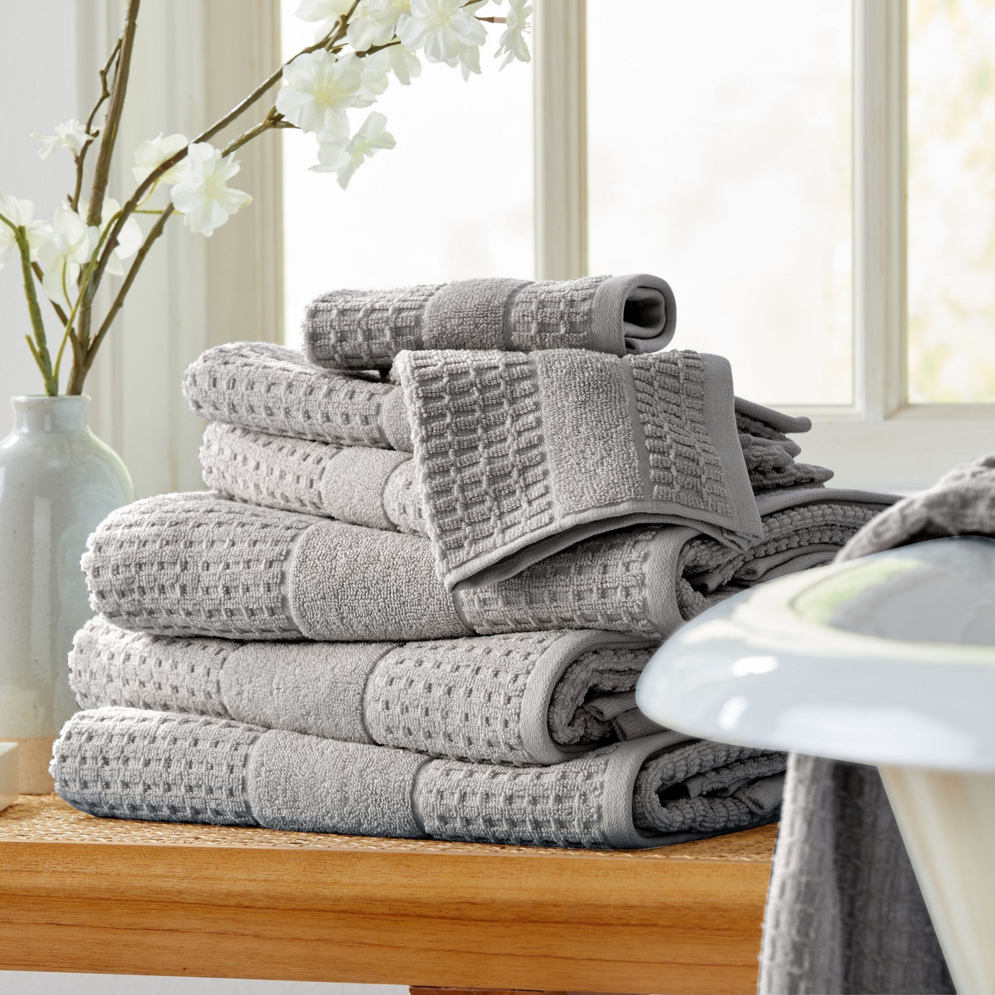Harper Collection Waffle Textured Bath Towels by Market & Place featuring premium 100% cotton construction with a stylish waffle weave texture. Available in multiple colors and set configurations, including bath towels, hand towels, and washcloths, shown folded, stacked, and styled to highlight their soft, plush, and highly absorbent design.