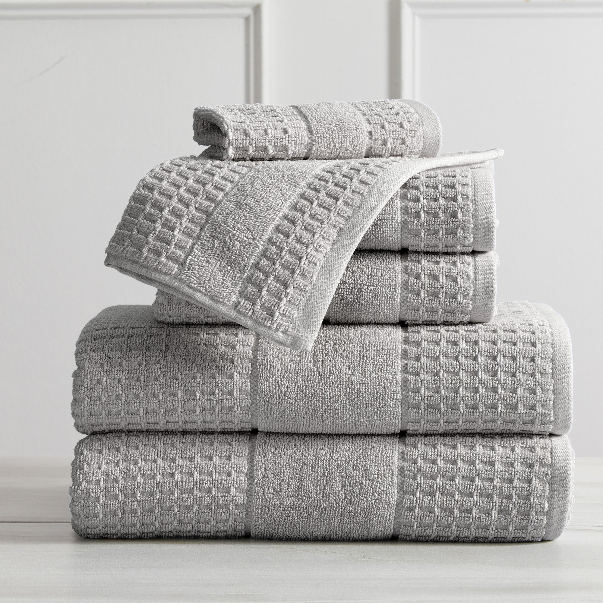 Harper Collection Waffle Textured Bath Towels by Market & Place featuring premium 100% cotton construction with a stylish waffle weave texture. Available in multiple colors and set configurations, including bath towels, hand towels, and washcloths, shown folded, stacked, and styled to highlight their soft, plush, and highly absorbent design.